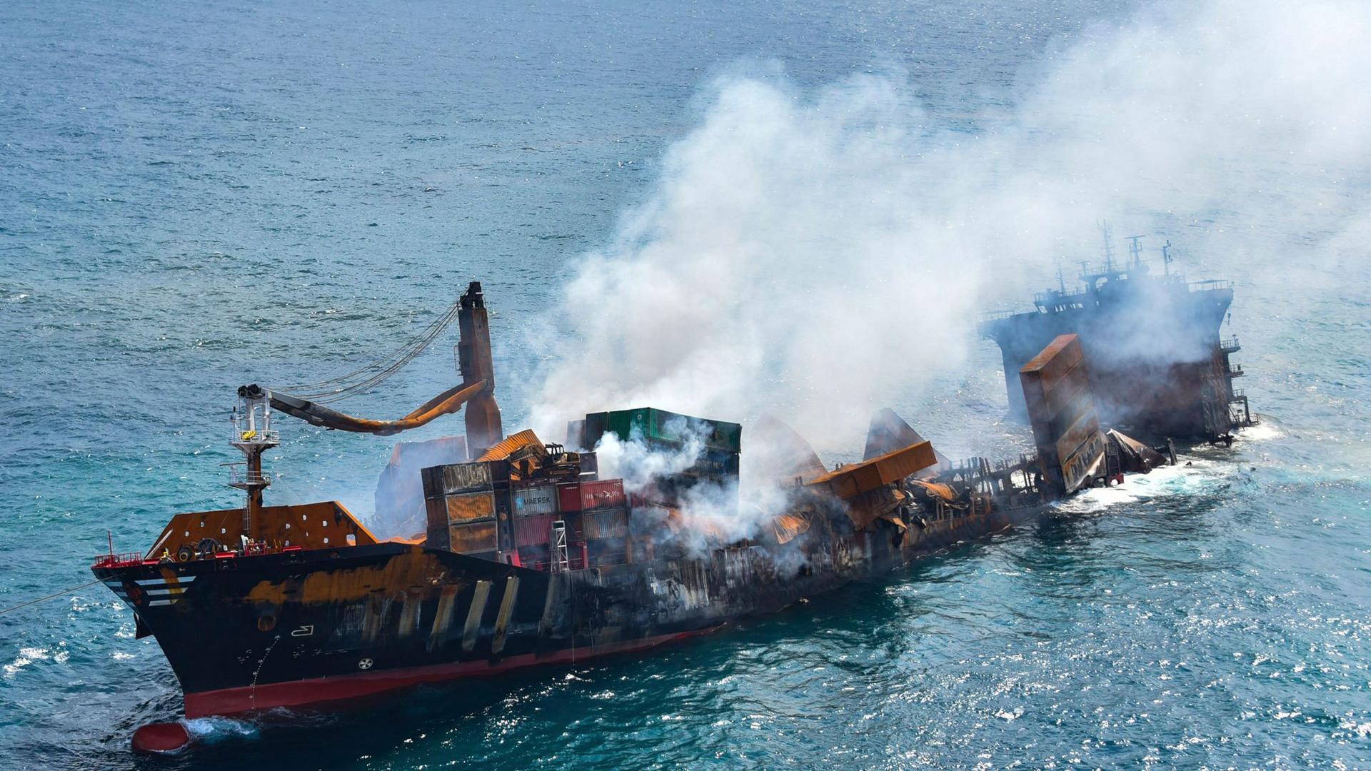 A large cargo ship is shown smoking and sinking into the ocean.