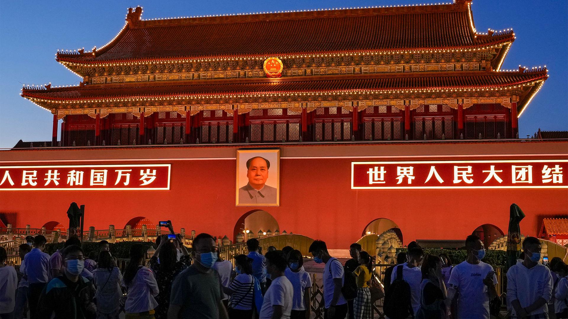 Red building in China with people in masks mingling in front of it
