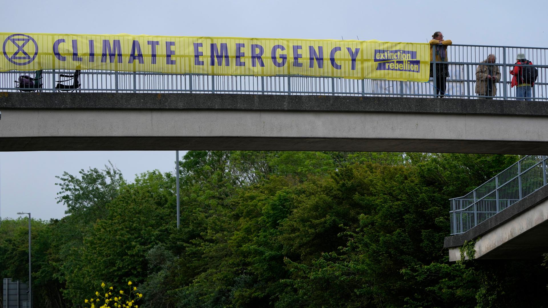 A climate banner covers the side of an overpass on a road leading to the G-7 summit near St. Ives, Cornwall, England, Thursday, June 10, 2021. 