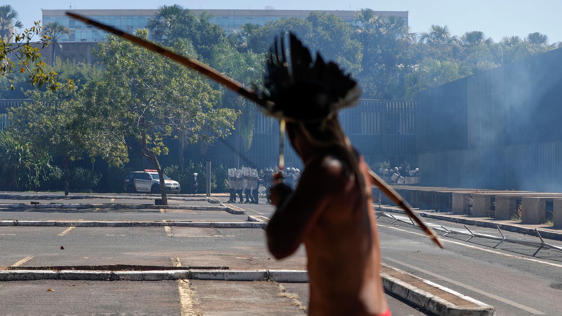 An Indigenous protester aims his bow an arrow at police outside Congress in Brasilia, Brazil, Tuesday, June 22, 2021. 