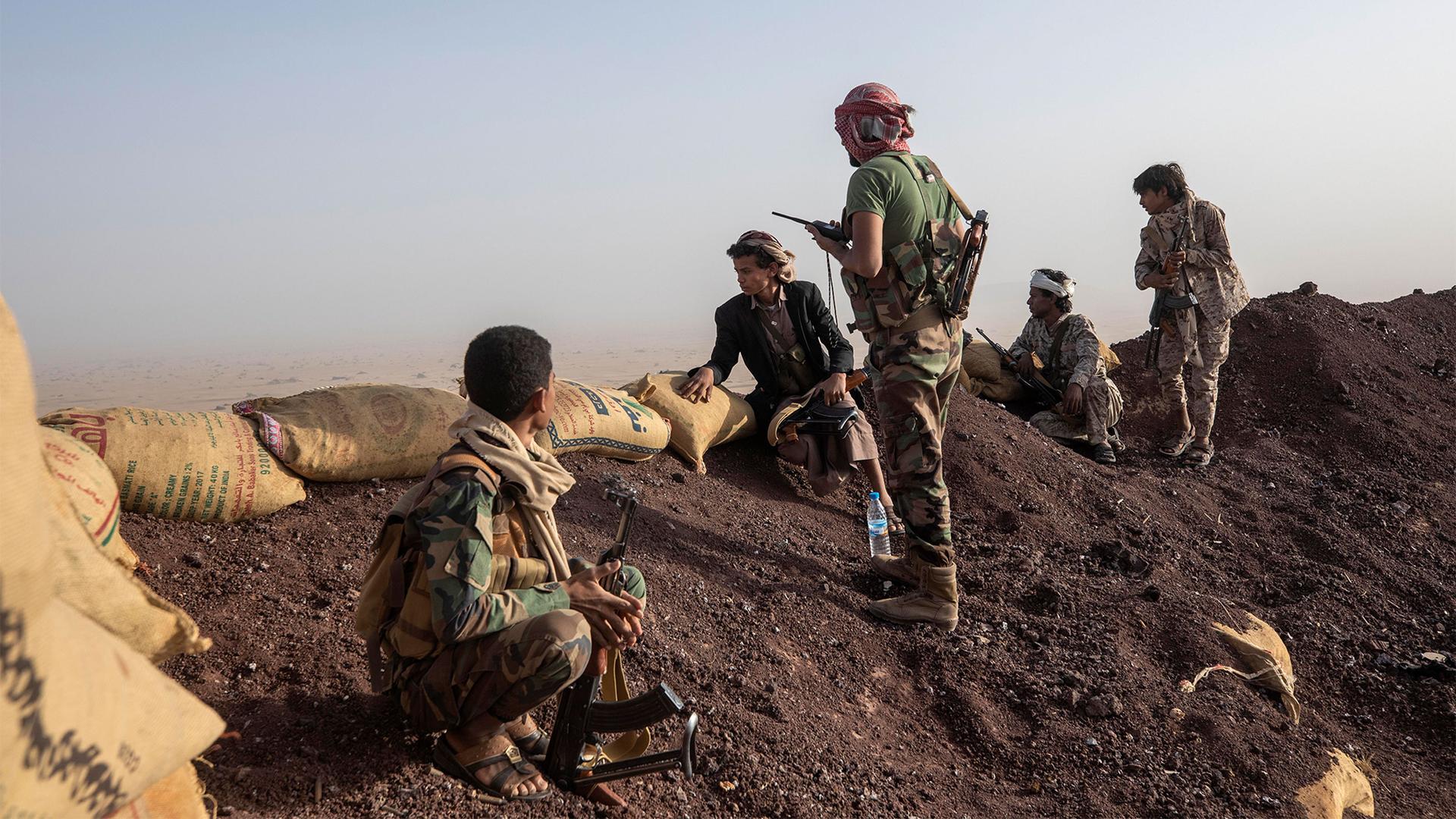 Yemeni fighters look over a mound of soil lined with sandbags