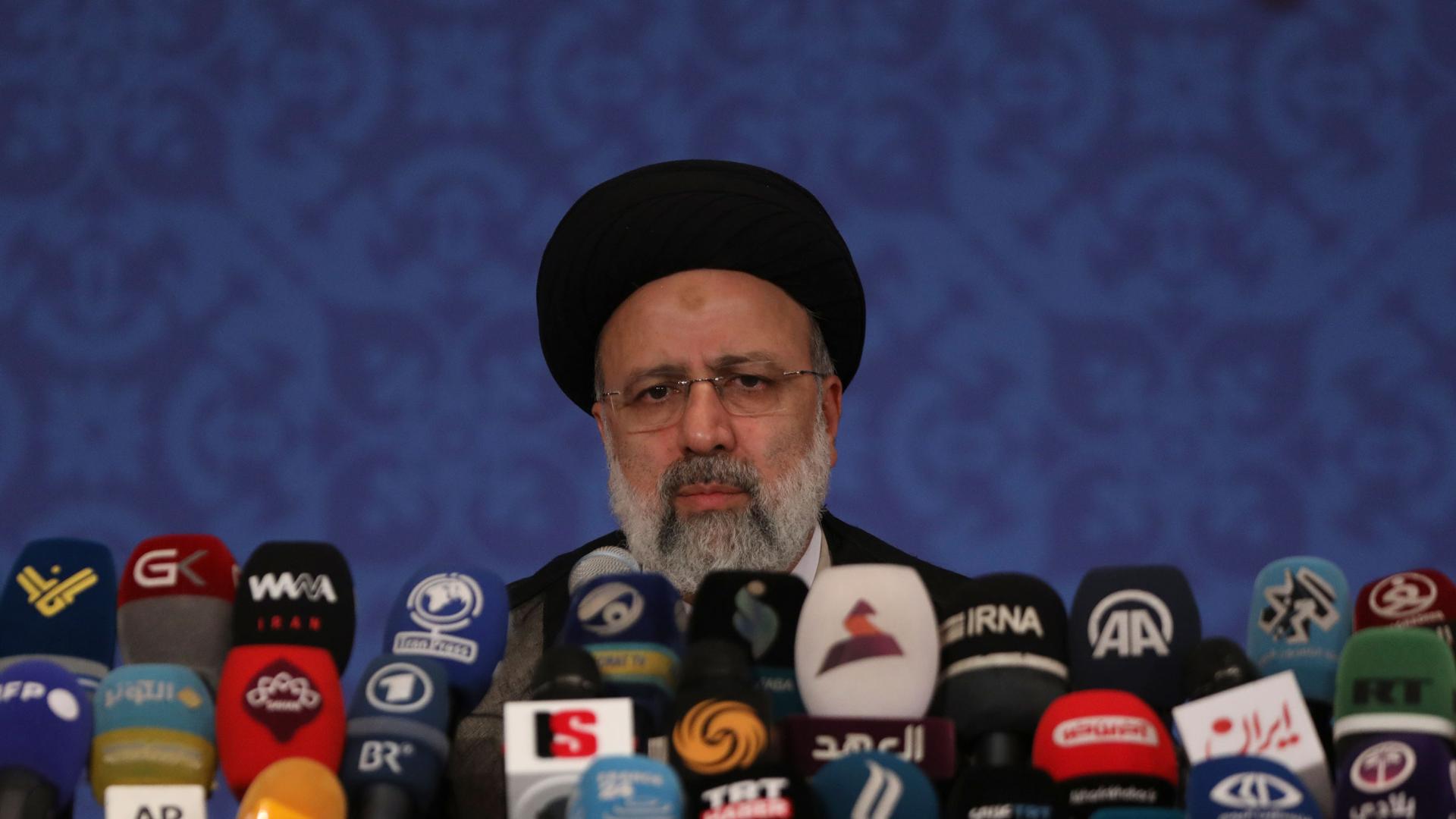 Iranian President Ebrahim Raisi is shown behind a large number of microphones.