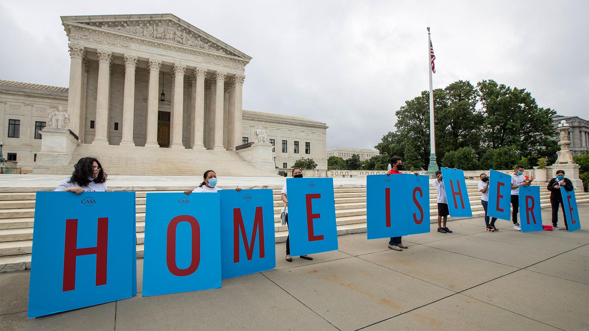 Students stand in a line in front of the US Supreme Court with signs that read "Home is here"