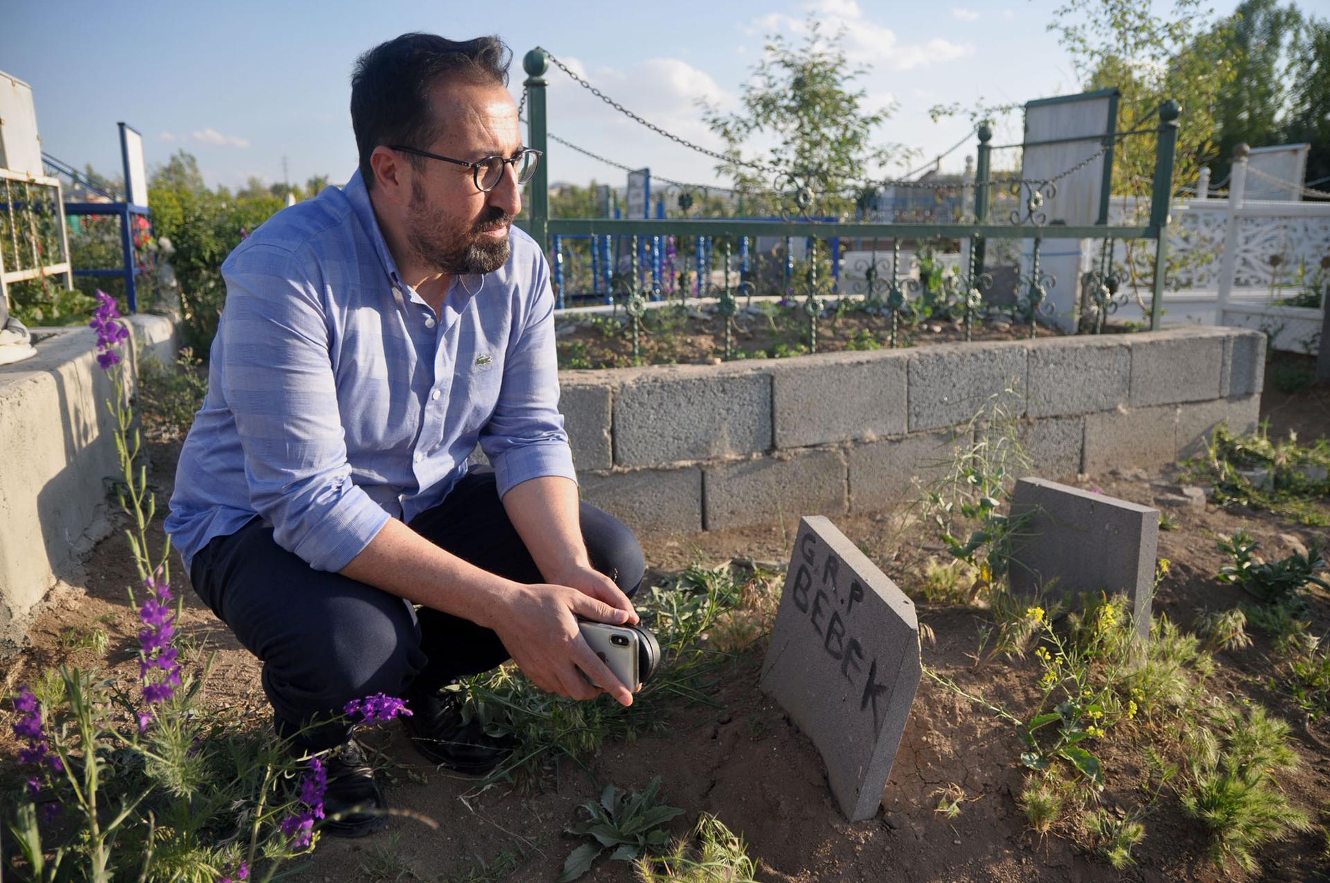 Mahmut Kaçan, an attorney with the Van Bar Association, sits near a grave for an infant who died on the journey to Turkey.