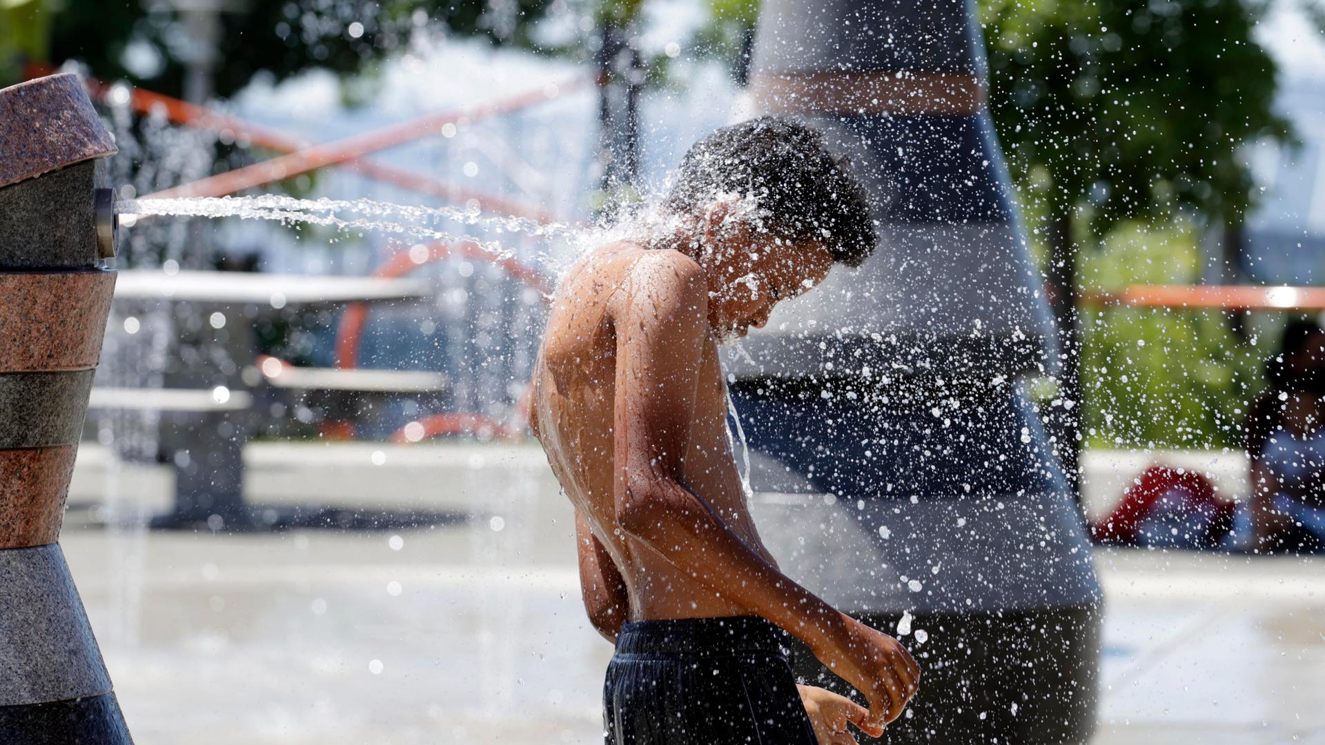 A young person cools off in the Yesler Terrace spray park during a heat wave hitting the Pacific Northwest, Sunday, June 27, 2021, in Seattle.