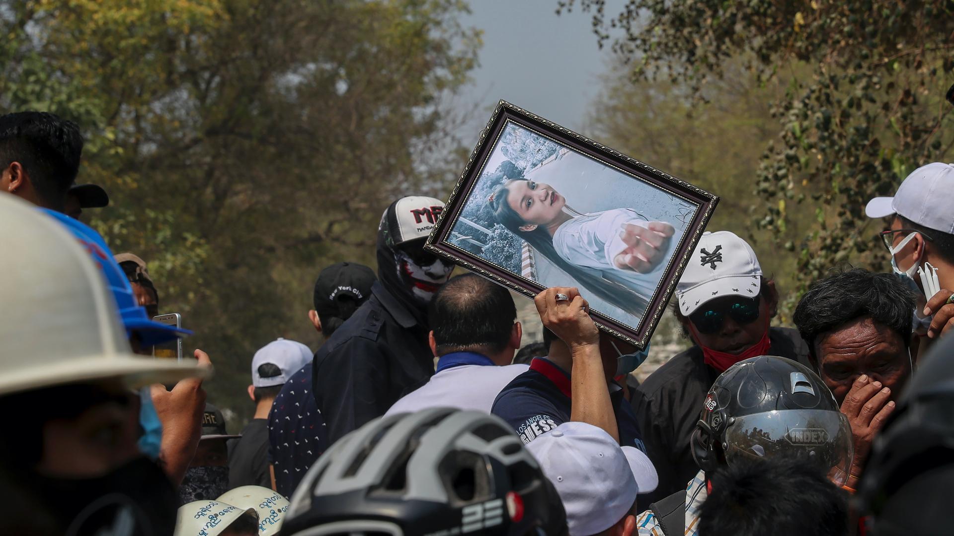 A man holds a picture of 19-year-old Kyal Sin, also known as Angel, during her burial in Mandalay, Myanmar