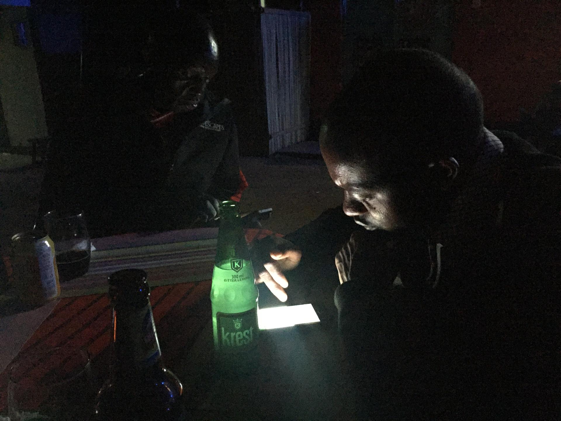 Two Maasai men check their phones at a local bar.
