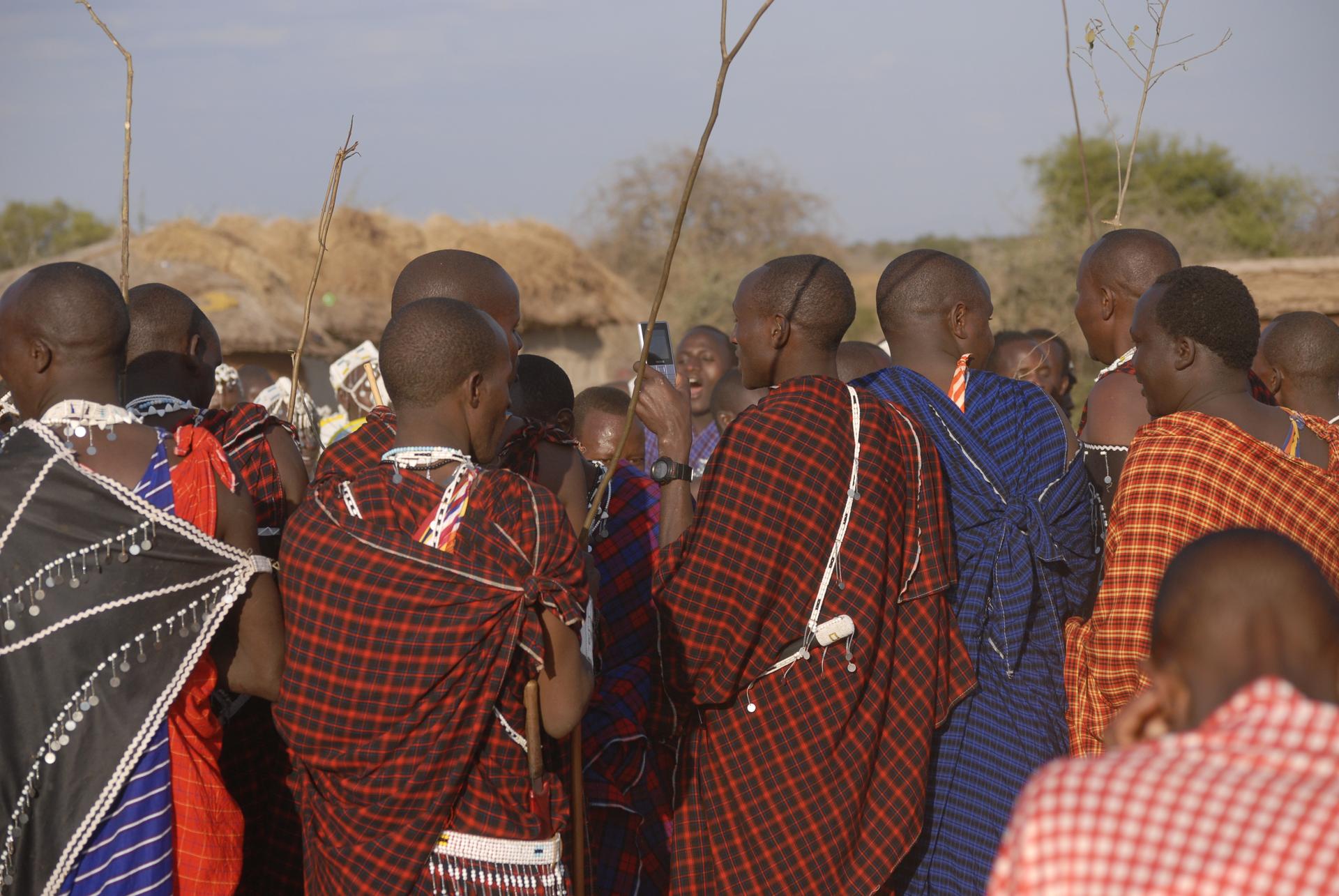 A young Maasai man checks his phone during a ceremonial dance.