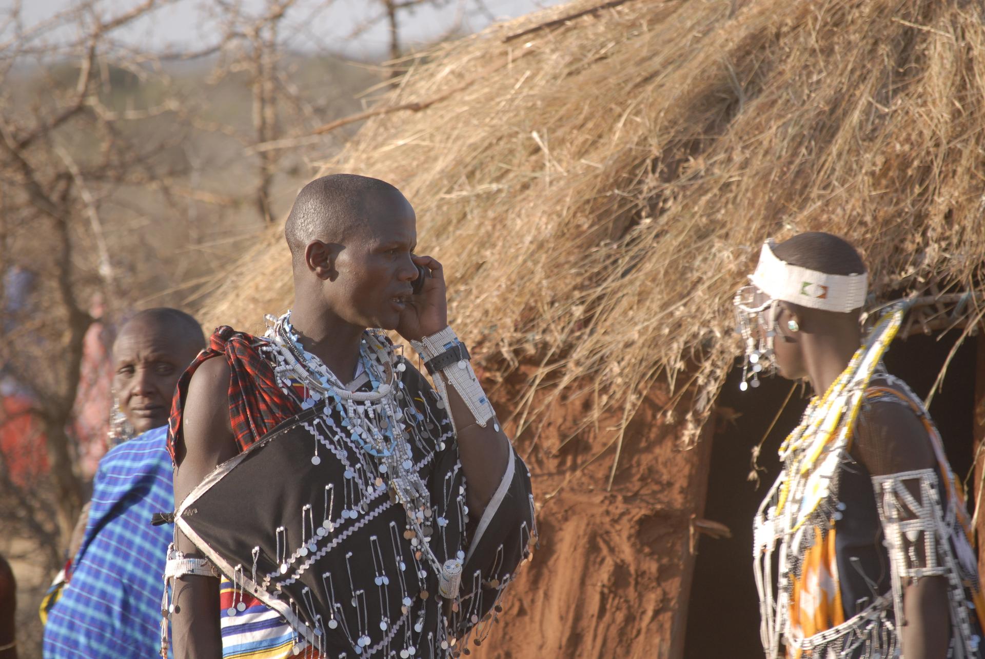 A Maasai man talks on his phone during a community gathering.