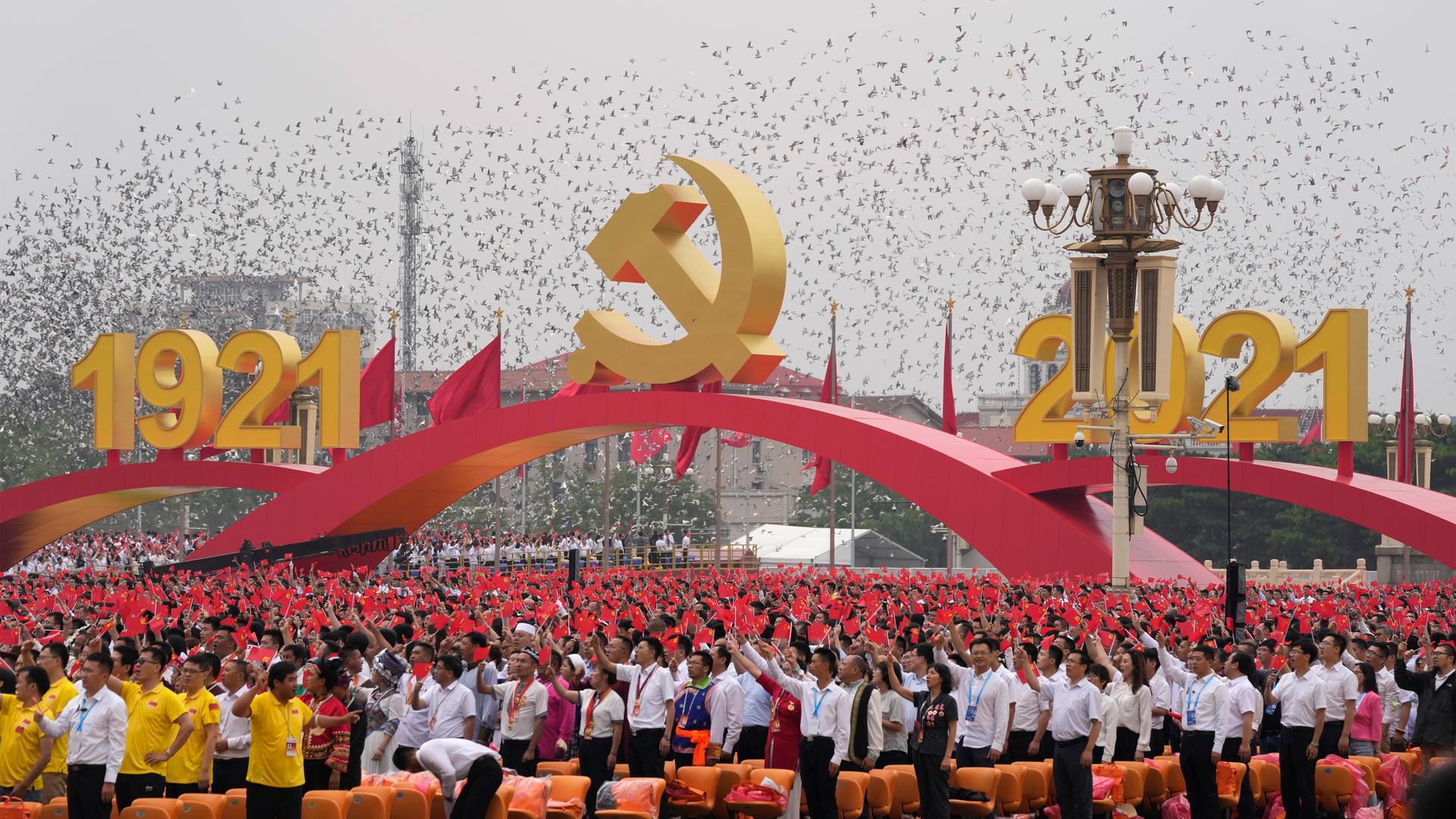 Attendees wave Chinese flags during a ceremony at Tiananmen Square to mark the 100th anniversary of the founding of the ruling Chinese Communist Party in Beijing