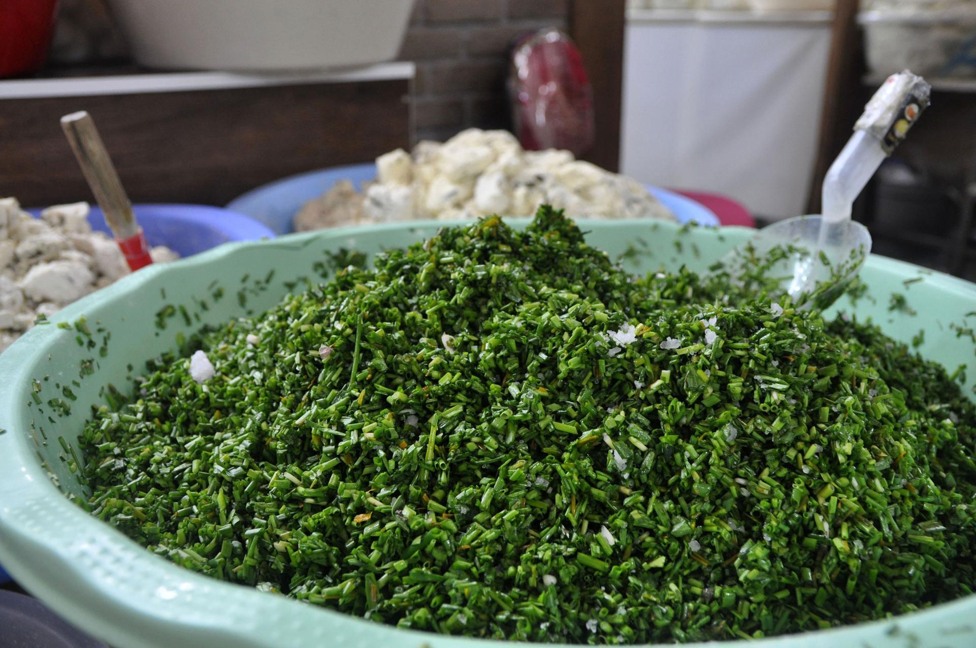 Green herbs used in Van Otlu Peyniri mixed in a green bowl.