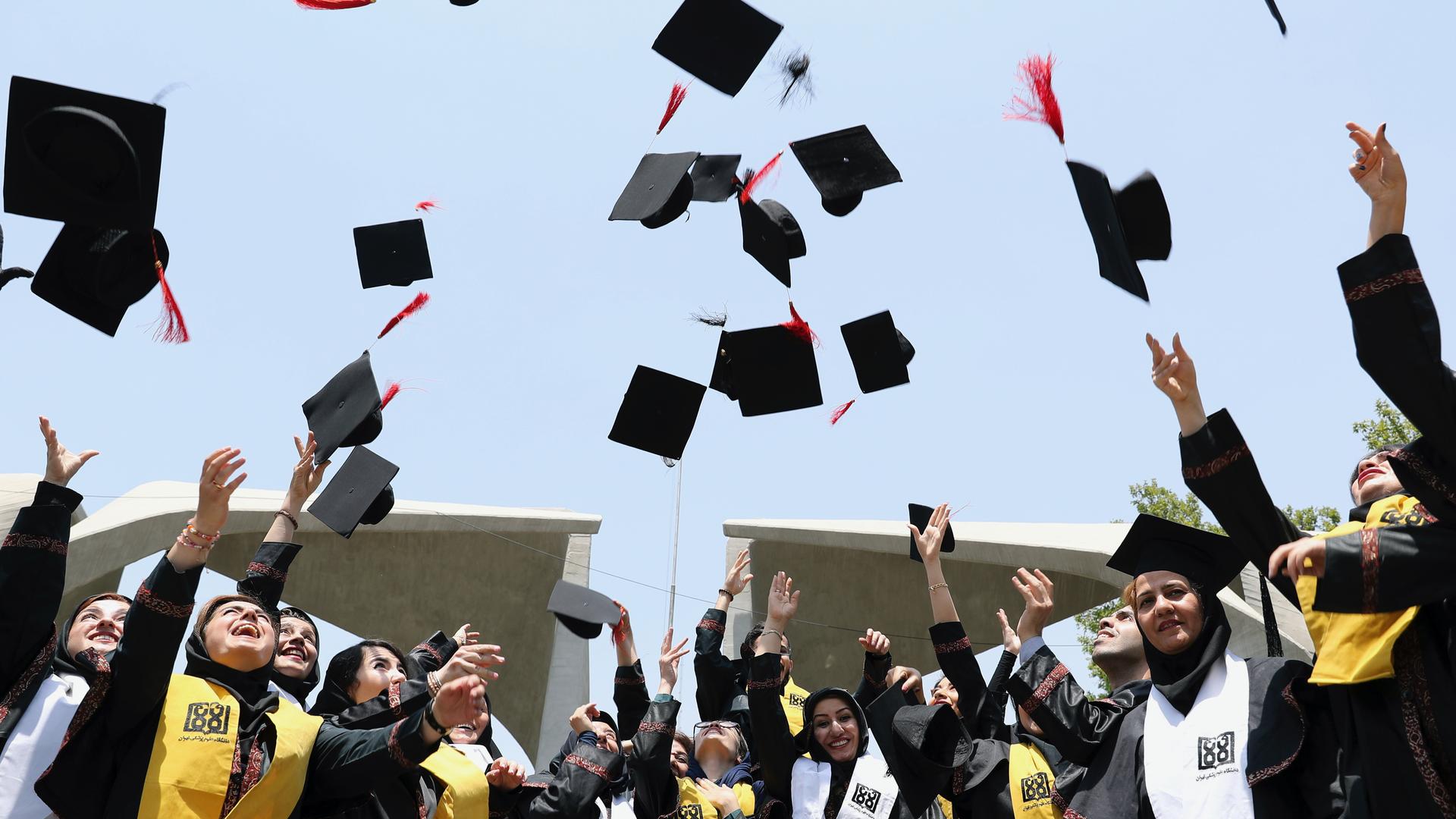 Students throw their hats in the air to celebrate a graduation in front of the main gate of Tehran University in Tehran, Iran, July 7, 2019.