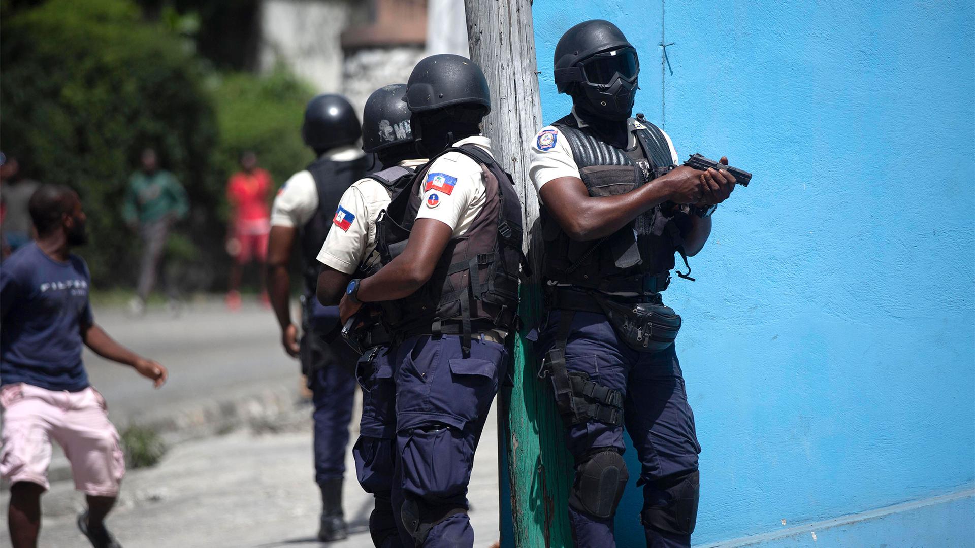 Police officers with guns drawn patrol the streets of Haiti
