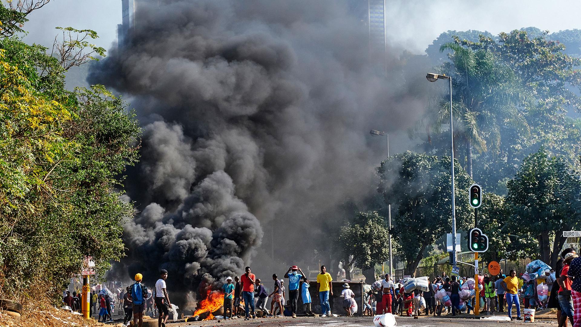 Looters outside a shopping centre alongside a burning barricade in Durban, South Africa