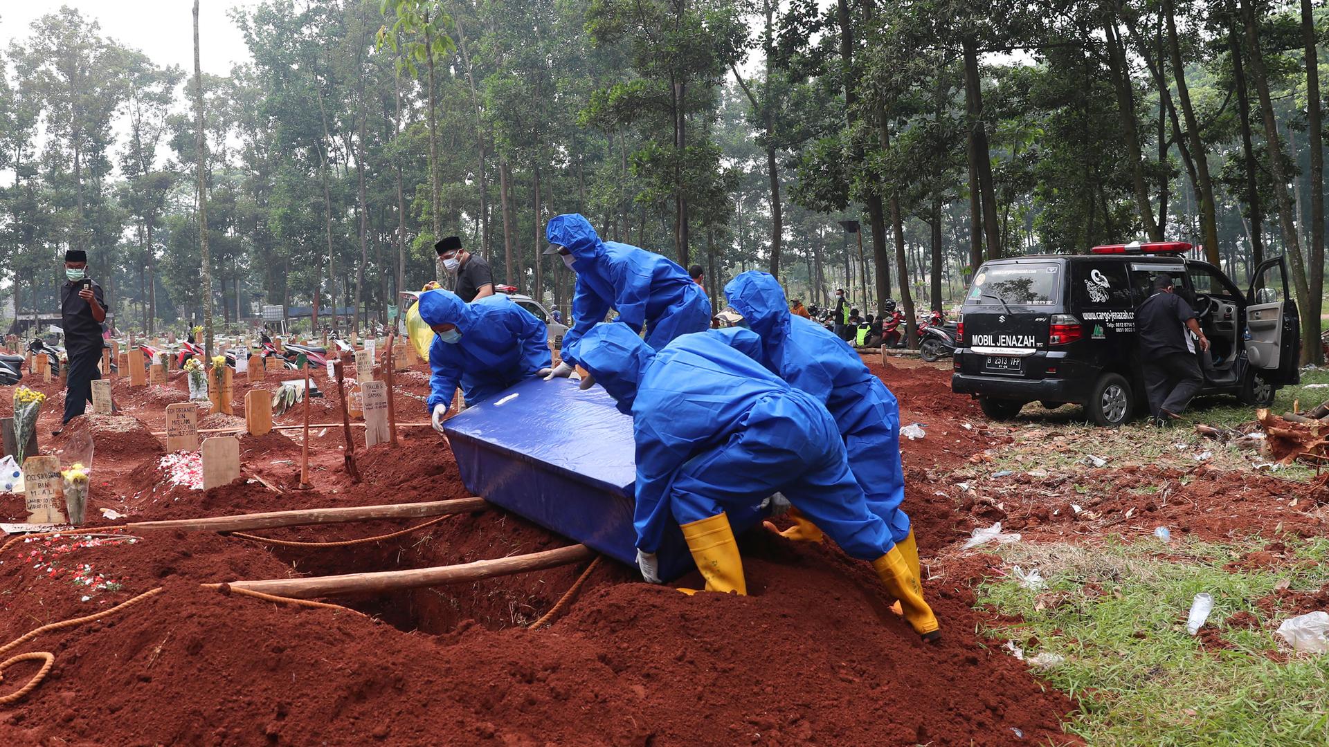 Workers in protective suits carry a coffin containing the body of a COVID-19 victim to a grave for a burial at Cipenjo cemetery in Bogor, West Java, Indonesia, Wednesday, July 14, 2021. 