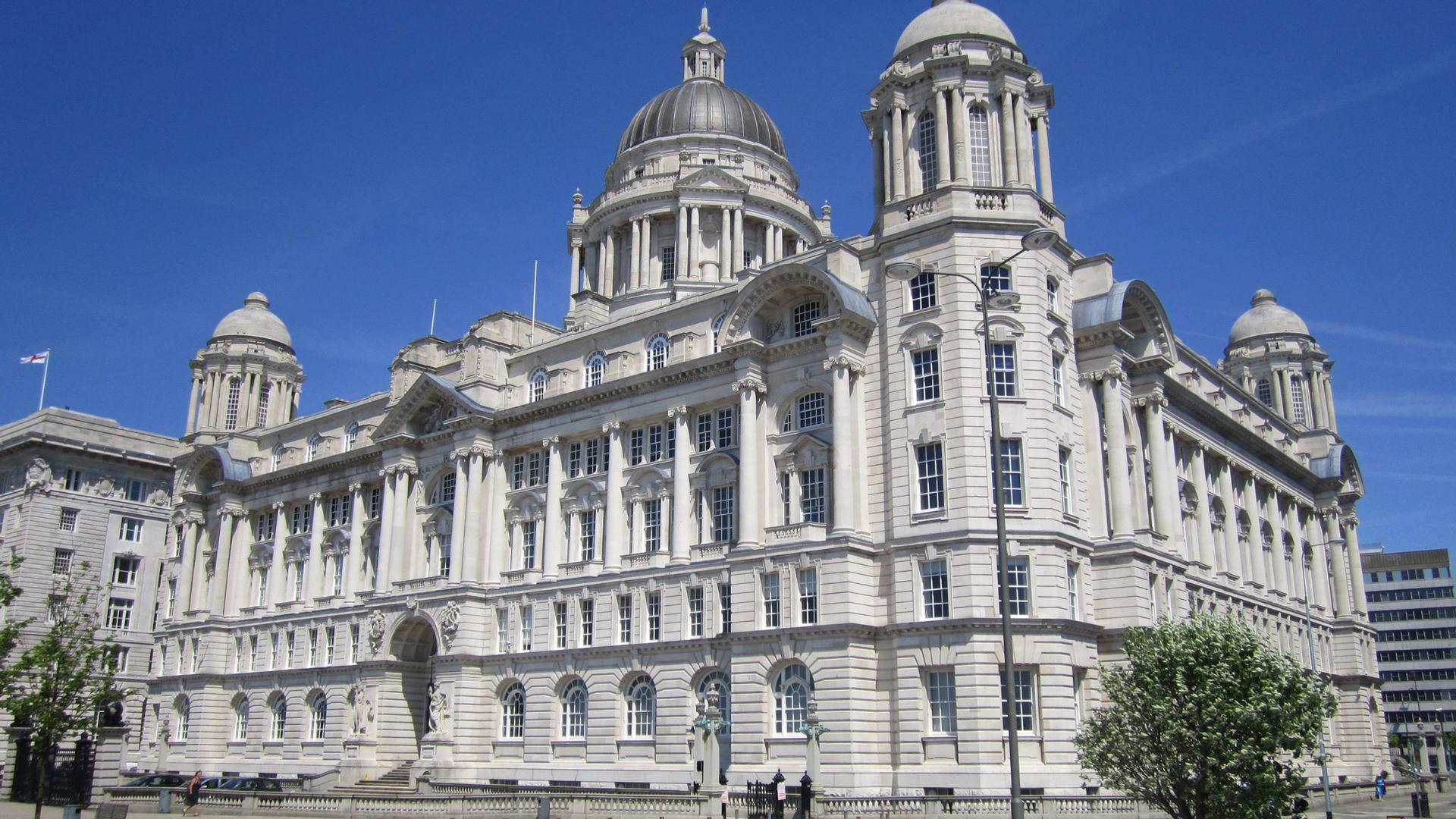 The large white stone facade of the Port of Liverpool building is shown with a silver dome on top.