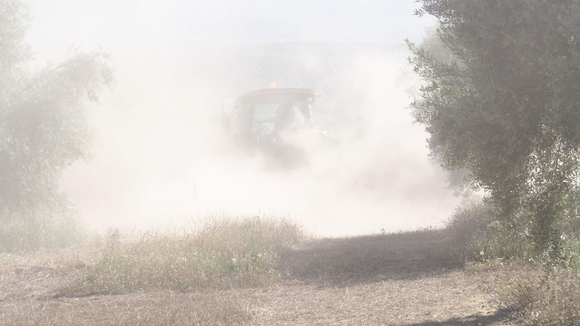 Topsoil dust kicks up from a tractor.
