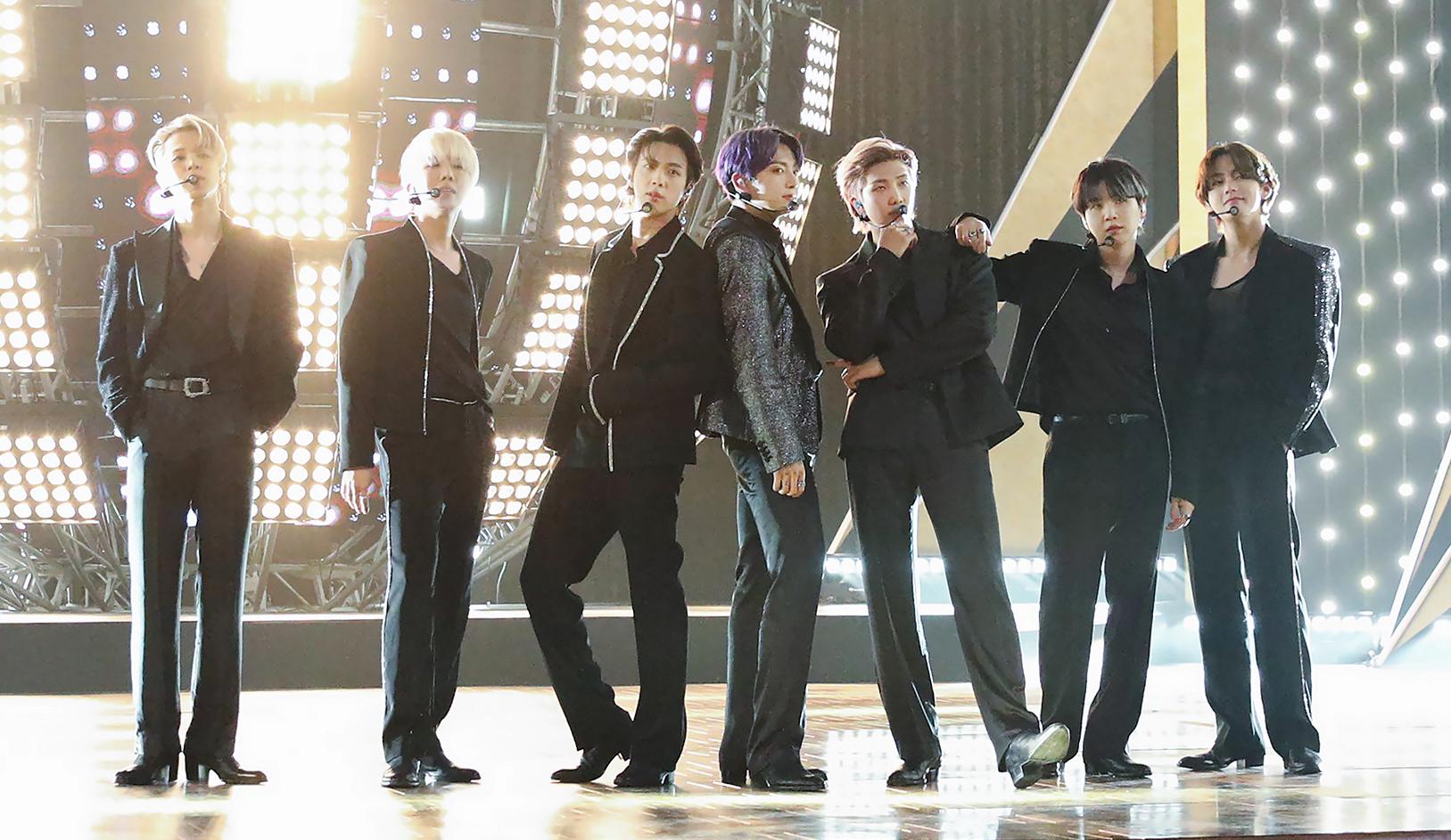 Members of BTS standing on a stage with dramatic lighting