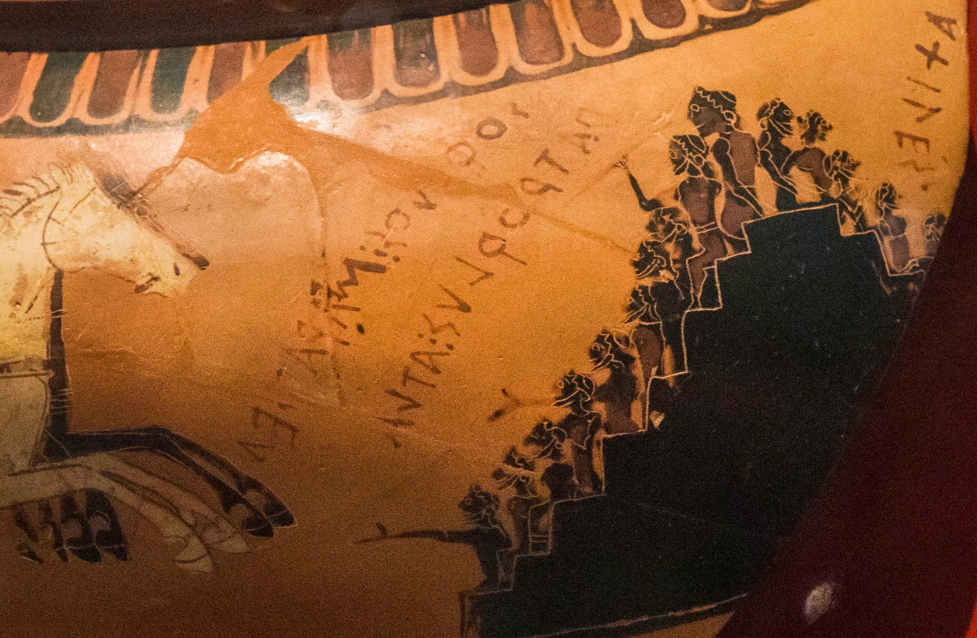 A detail of a Greek cauldron depicts spectators cheering on a chariot race.