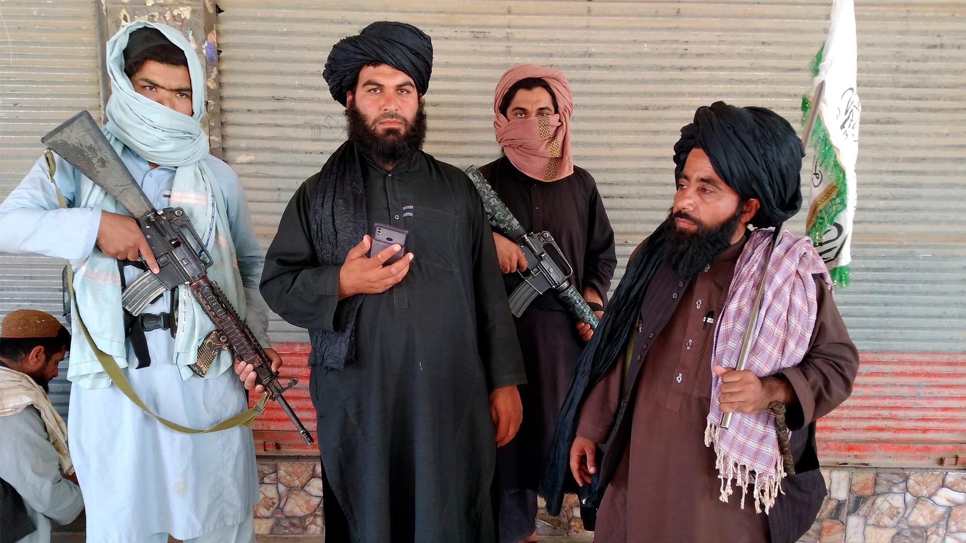 Four men are shown wearing traditional Afghani robes with two men holding large weapons.