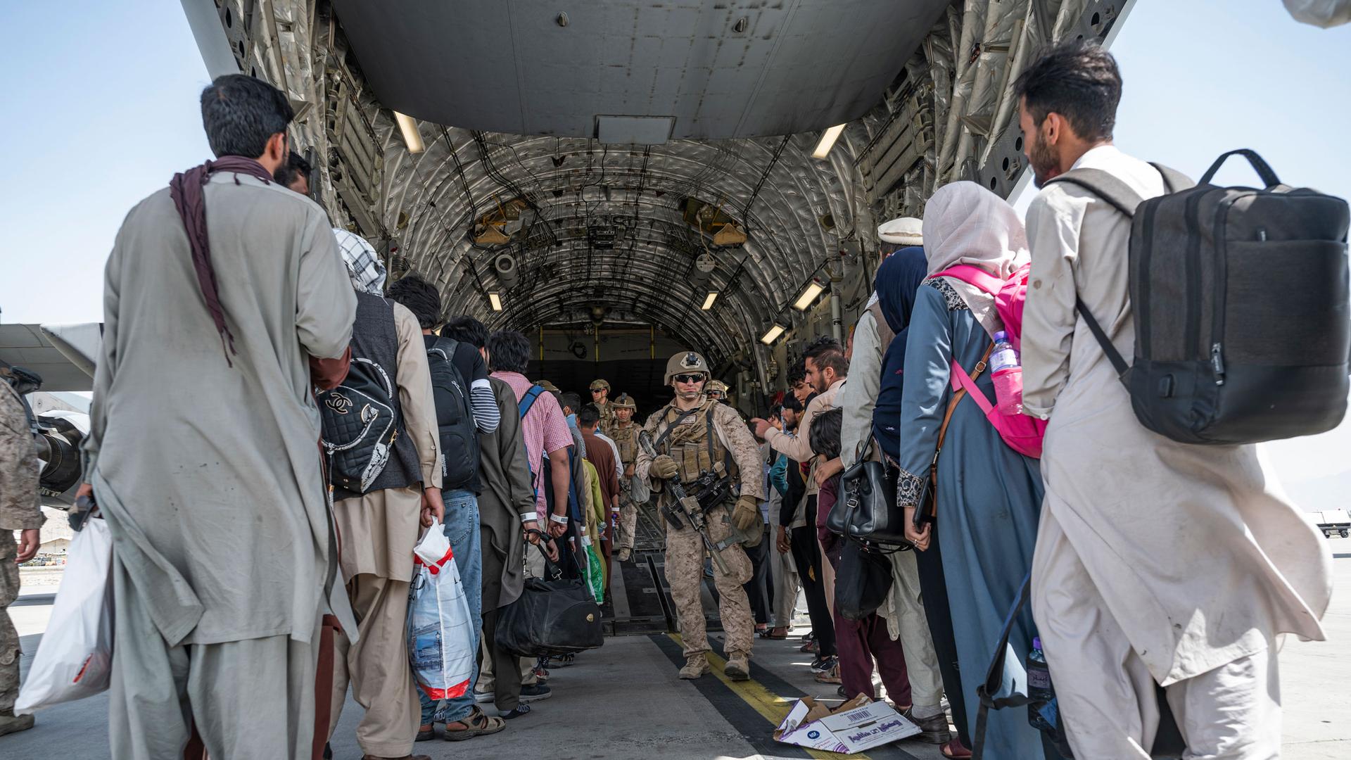 In this Aug. 21, 2021, image provided by the U.S. Air Force, US Airmen and U.S. Marines guide evacuees aboard a US Air Force C-17 Globemaster III in support of the Afghanistan evacuation at Hamid Karzai International Airport in Kabul, Afghanistan. 