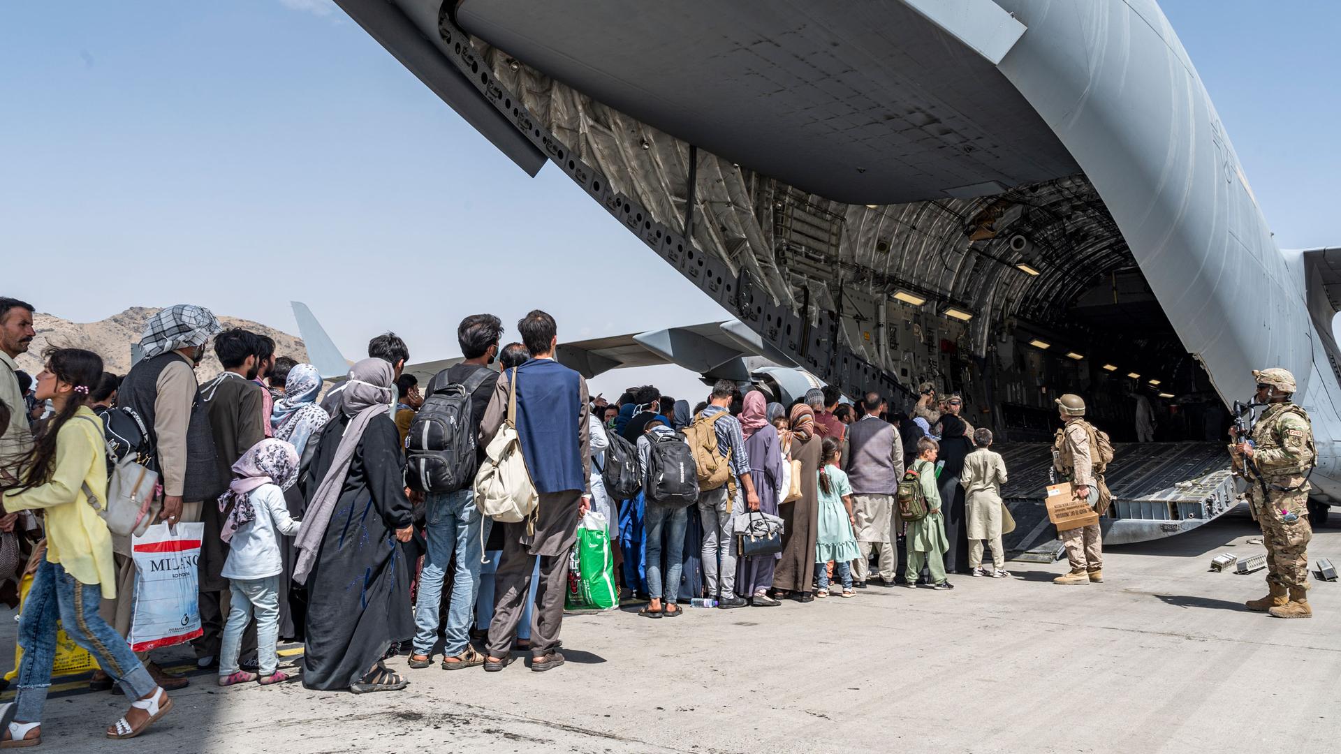 In this Aug. 21, 2021, image provided by the U.S. Air Force, US Airmen and U.S. Marines guide evacuees aboard a U.S. Air Force C-17 Globemaster III in support of the Afghanistan evacuation at Hamid Karzai International Airport in Kabul, Afghanistan. 