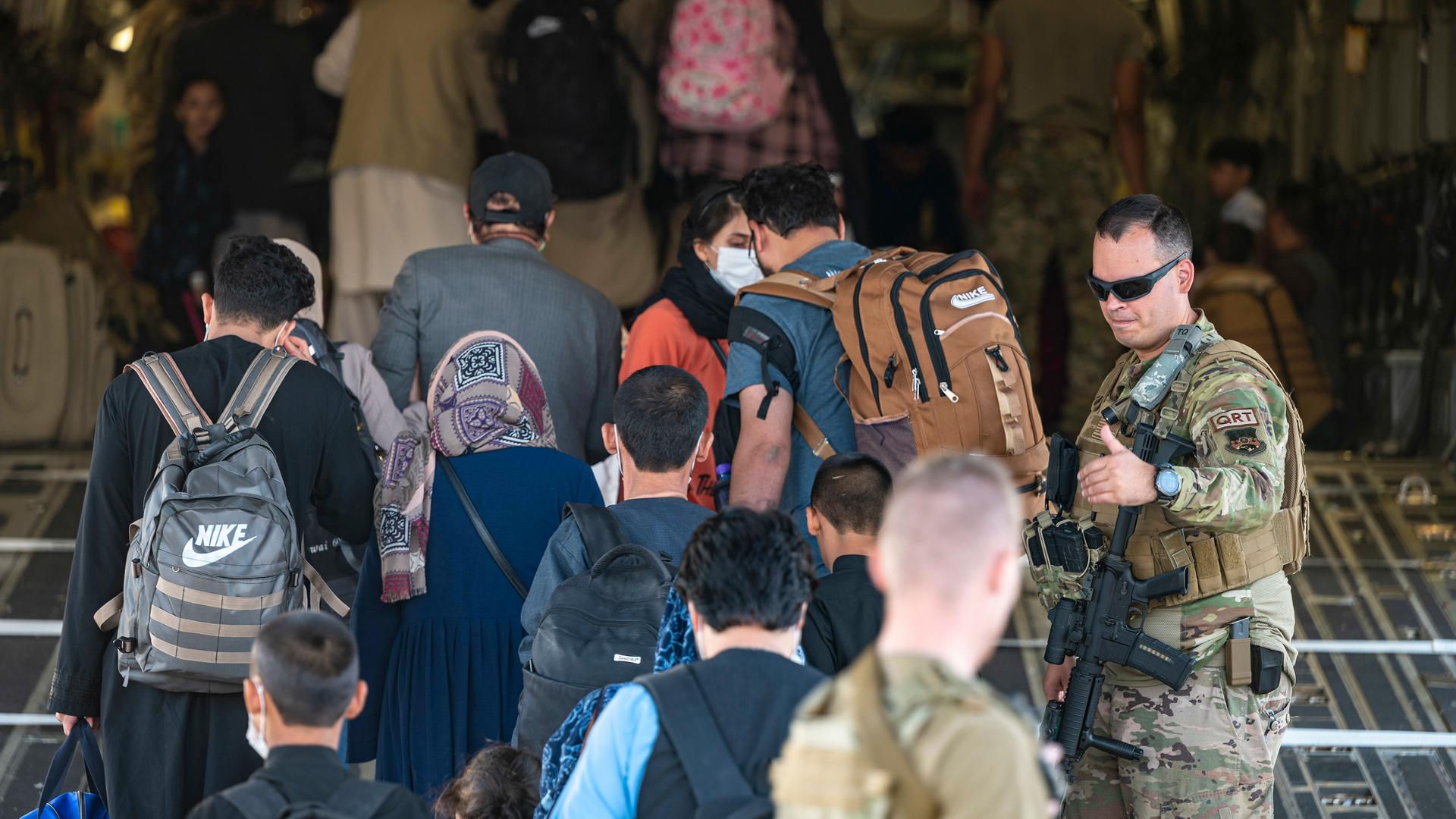 US Air Force airmen guide evacuees aboard a US Air Force C-17 Globemaster III at Hamid Karzai International Airport in Kabul, Afghanistan