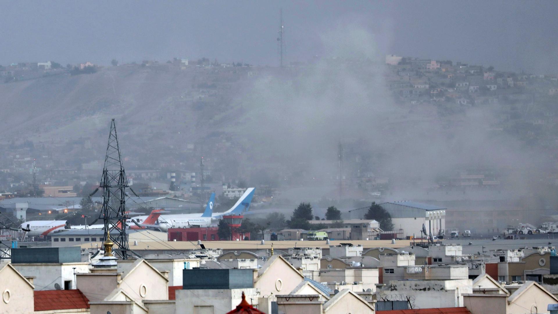 A wide-framed photograph is shown of Kabul with the airport in the distance and smoke rising.