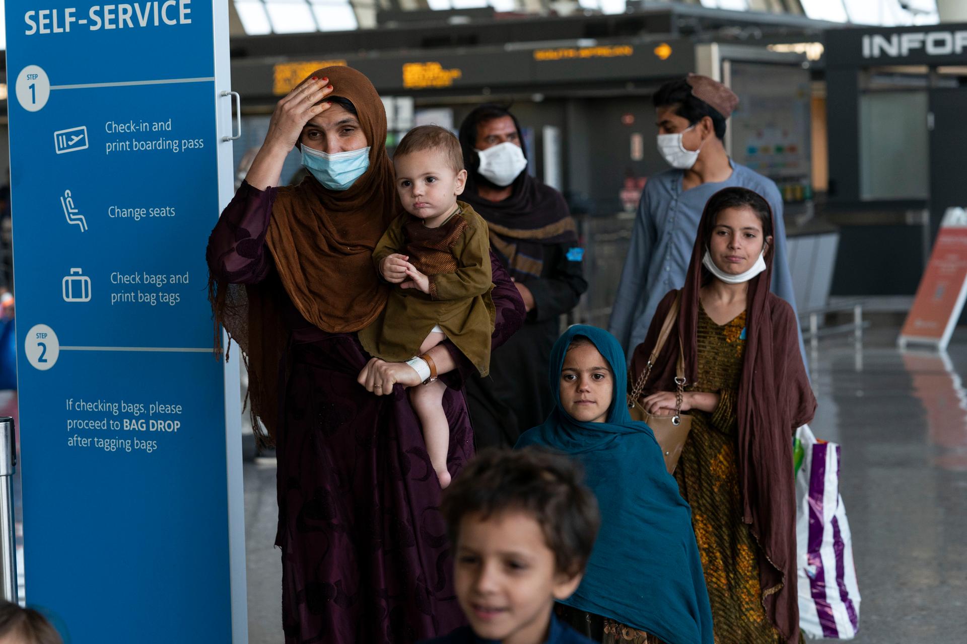 Families evacuated from Kabul, Afghanistan, walk through the terminal before boarding a bus after they arrived at Washington Dulles International Airport, in Chantilly, Virginia, Aug. 27, 2021.