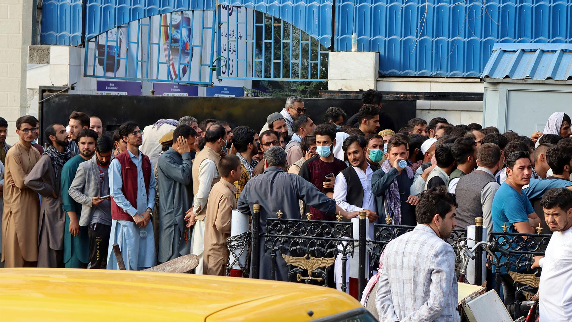 Afghans wait in long lines for hours to try to withdraw money, in front of a Bank in Kabul, Afghanistan