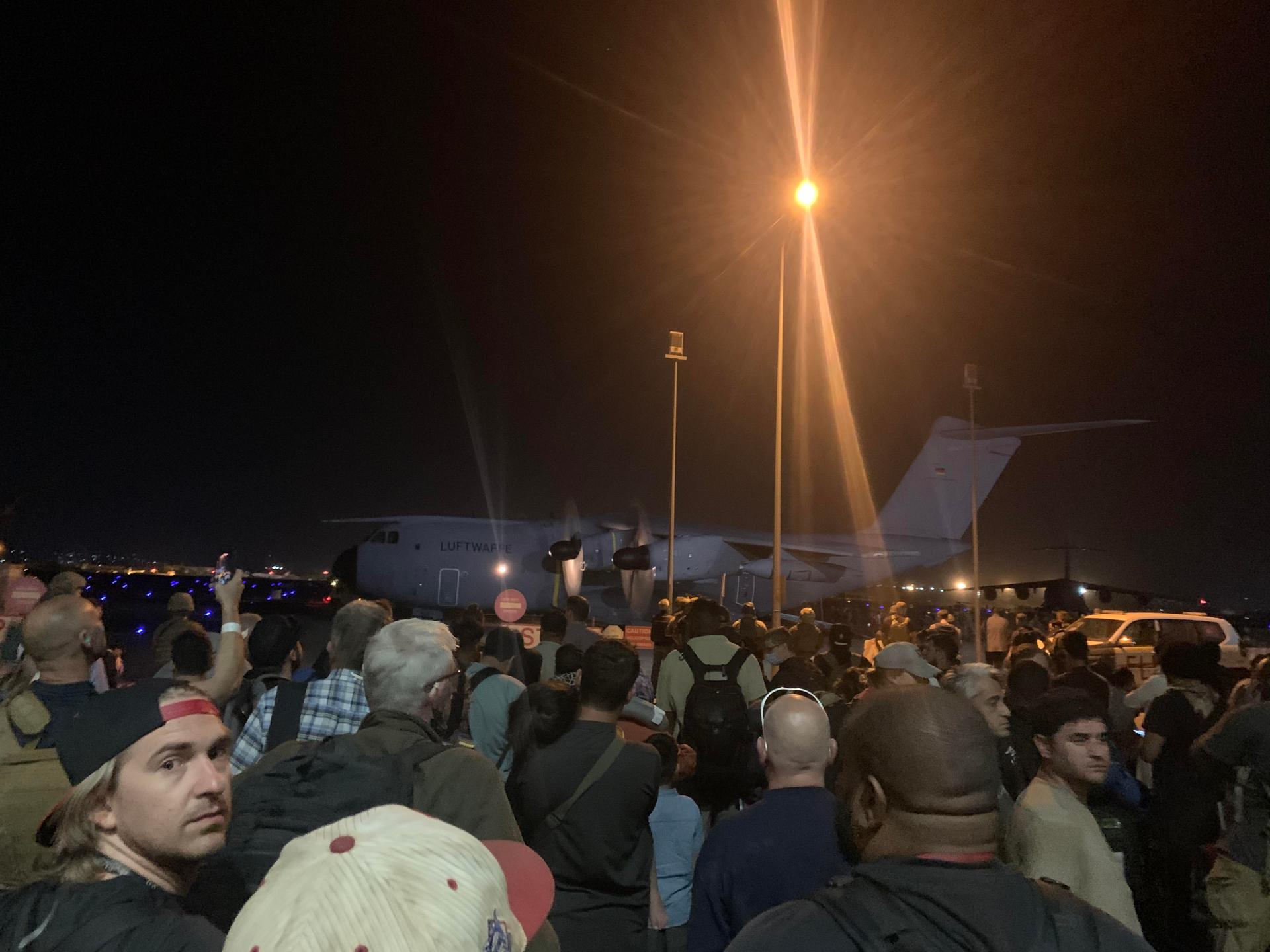 Crowd at night gathered around a Luftwaffe transport plane