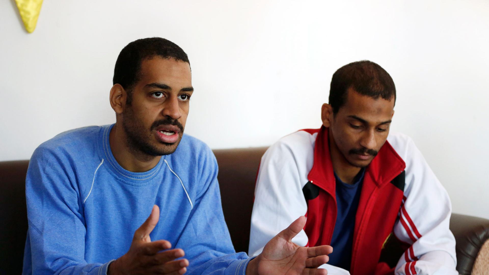 Two men are shown sitting on a sofa with Alexanda Amon Kotey on the left, wearing a blue sweatshirt.