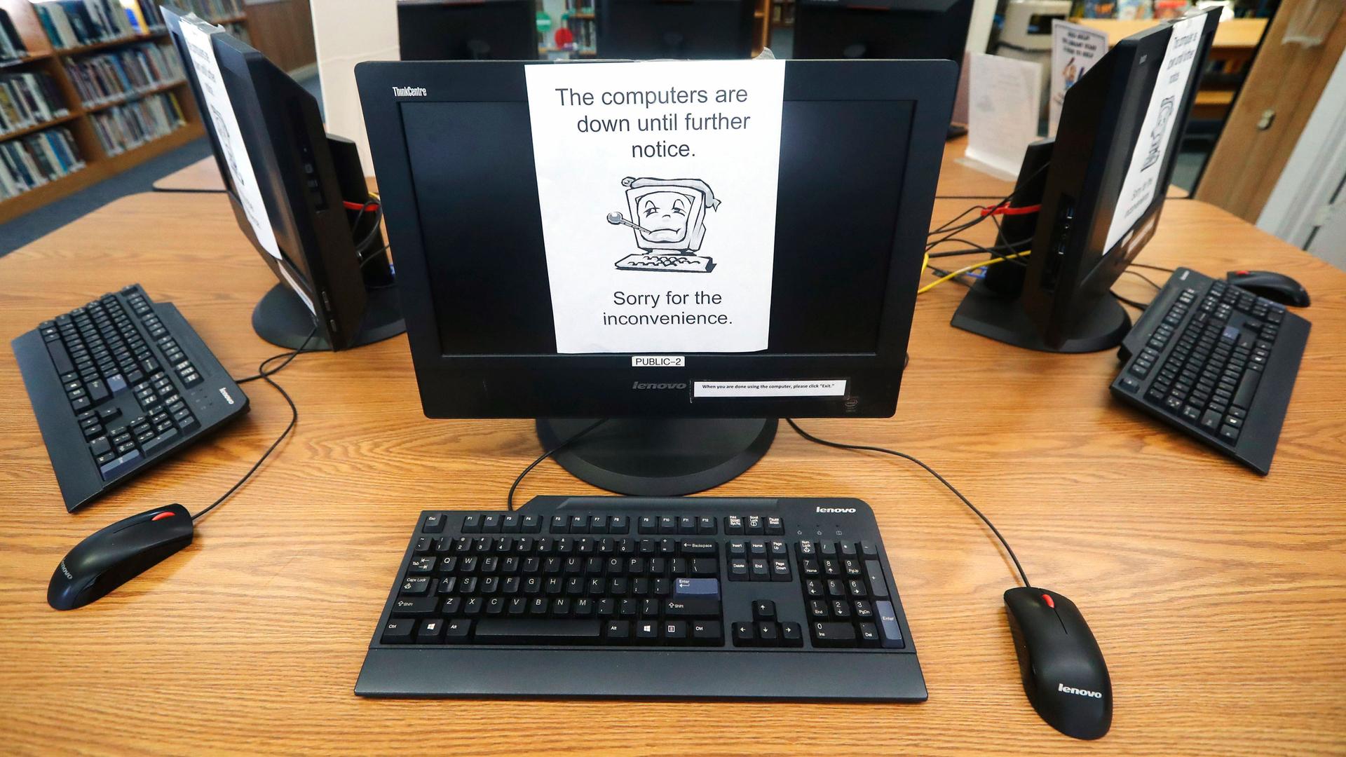 In this Aug. 22, 2019, file photo, signs on a bank of computers tell visitors that the machines are not working at the public library in Wilmer, Texas. 