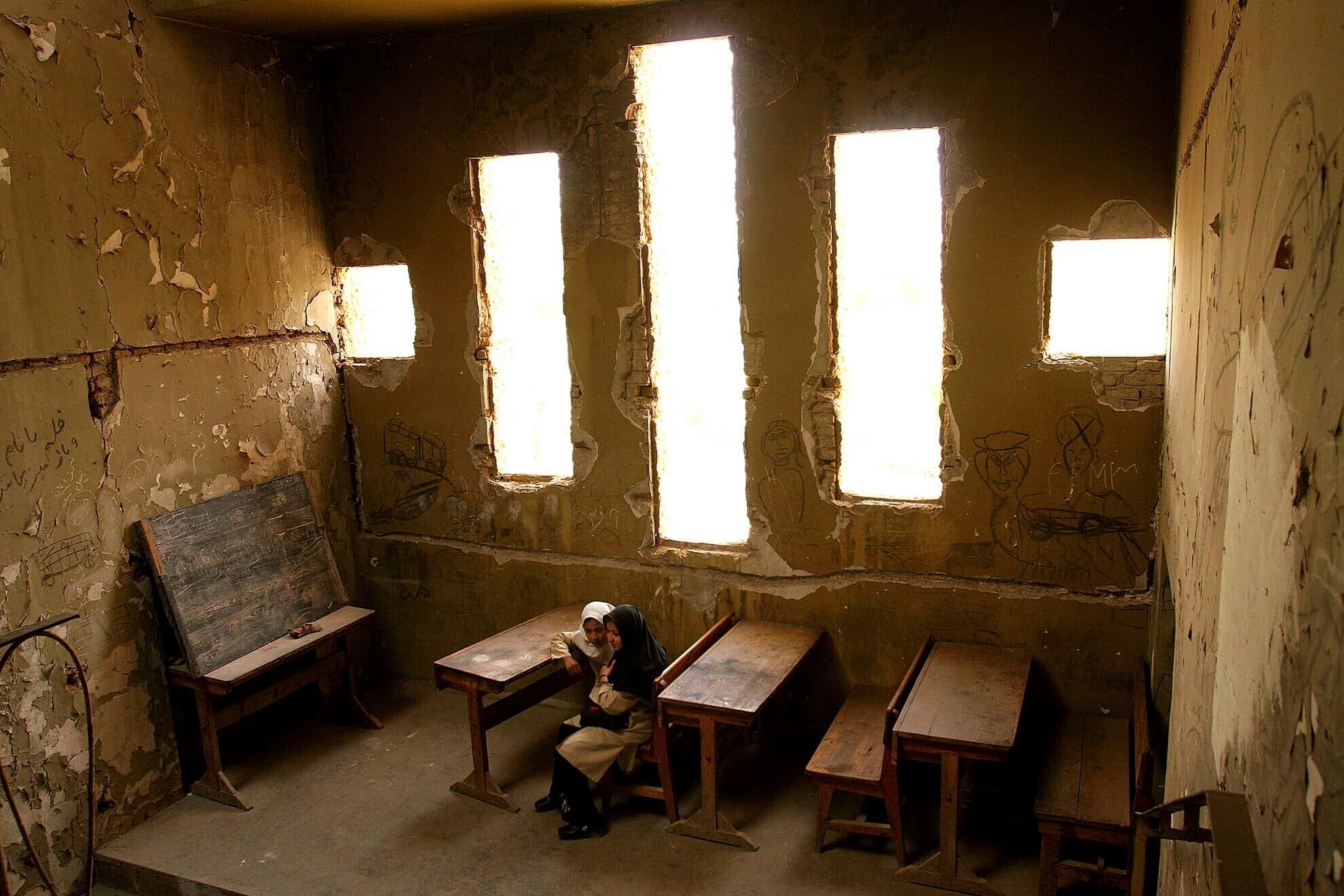 Basera, 13, right, and Saira, 10, wait for their class to begin at Loy Ghar school, in the bombed-out carcass of the Kabul Theater in Afghanistan's capital, April 20, 2005. The bullet-riddled building became a place of hope for more than 400 students look