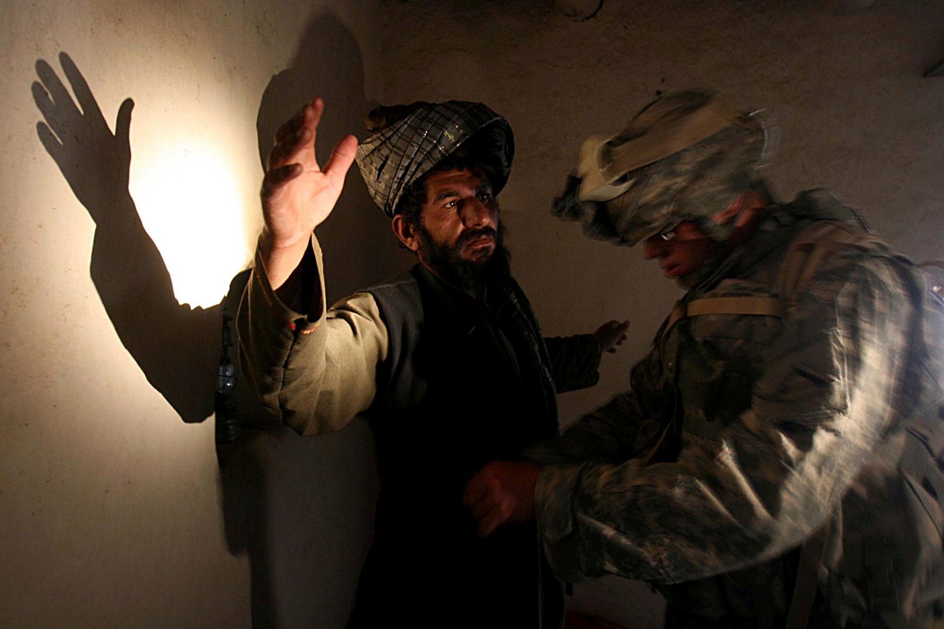 A US soldier of B company, 4th Infantry Regiment frisks an Afghan man in his house during a search operation in Sinan village in Zabul province, southeastern Afghanistan, on April 2, 2007. 