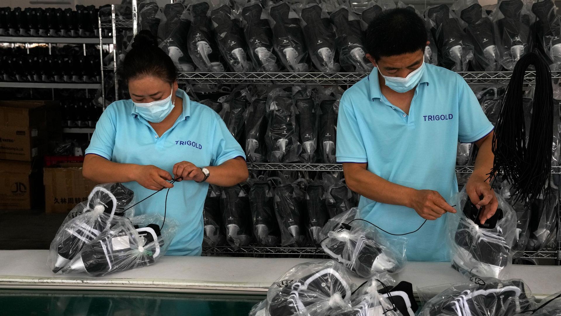 Workers packing ice-skating shoes at a manufacturing factory in the ice and snow sports equipment industry park in Zhangjiakou, in northwestern China's Hebei province, Thursday, July 15, 2021. 