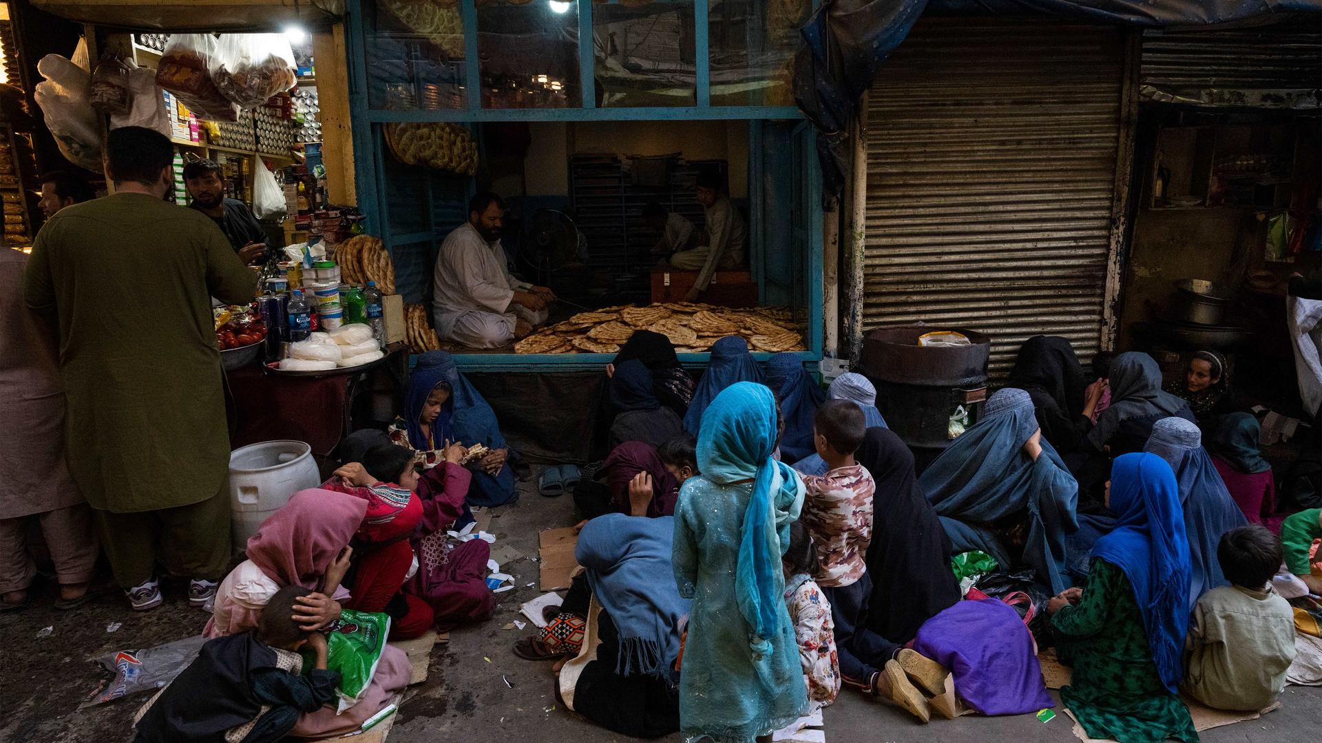 Afghan women and children sit in front of a bakery waiting for bread donations in Kabul's Old City, Afghanistan, on Sept. 16, 2021.