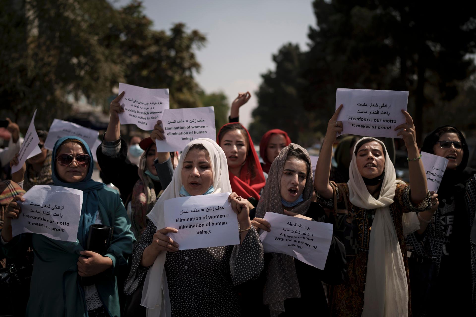 Afghan women march and hold signs in rally