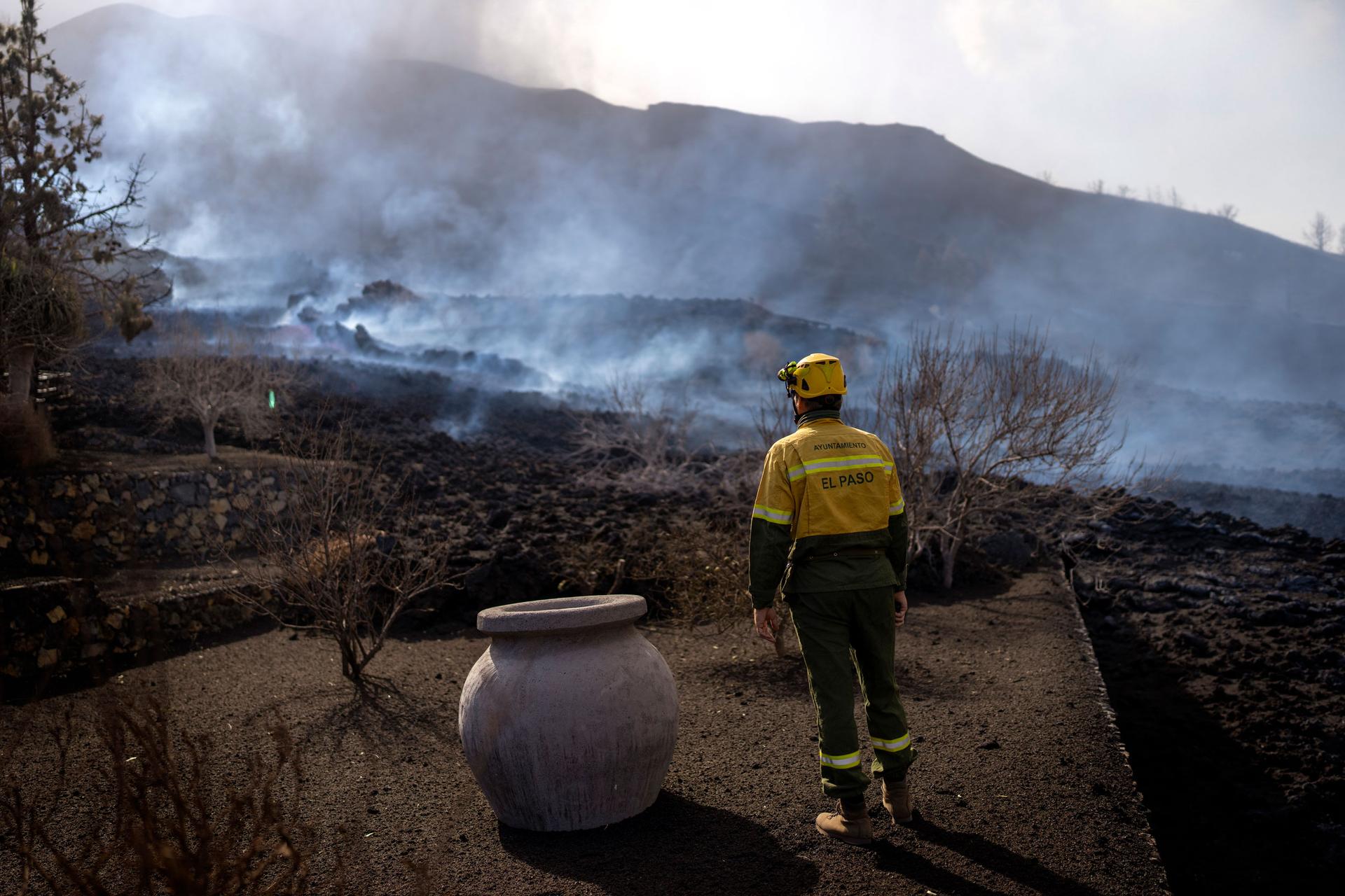 A municipal worker looks as smoke rises after a volcano erupted, near El Paso on the island of La Palma in the Canaries, Spain, Tuesday, Sept. 21, 2021. 