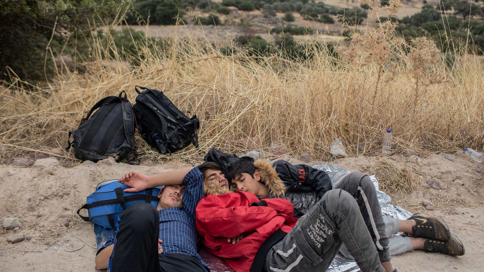In this Monday, Oct. 7, 2019 photo, exhausted Afghan youths sleep on the ground near the town of Madamados after their arrival with other migrants and refugees on a rubber boat from Turkey, at Lesbos Island, Greece.