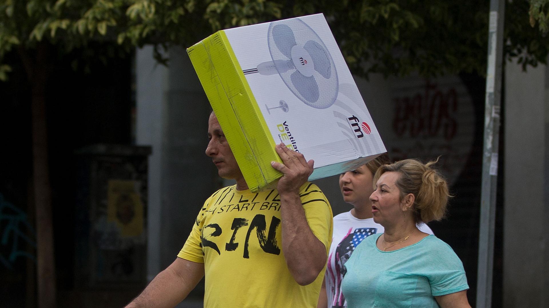 In this June 15, 2017 file photo, a man carries a boxed electric fan in Madrid, Spain. Spanish consumers are fretting over record-high power prices. 