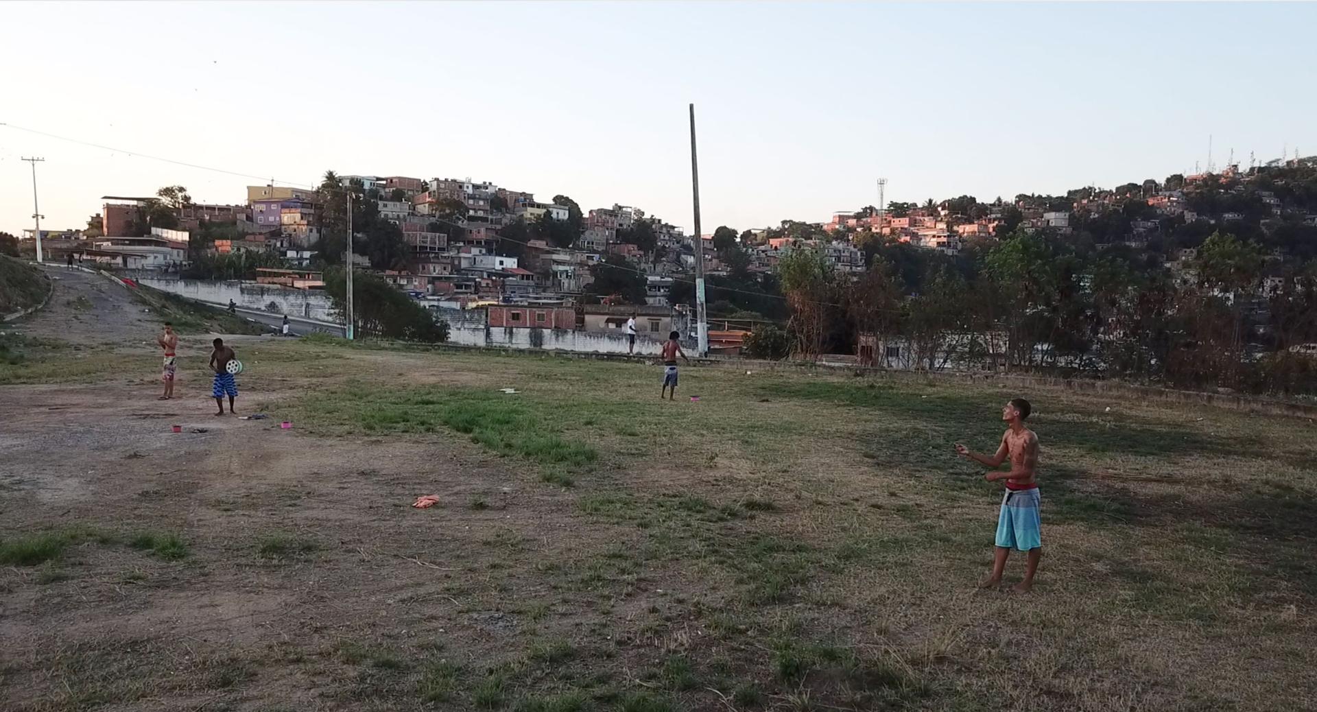Teenage boys fly kites in an open field in Rio de Janeiro, Brazil.