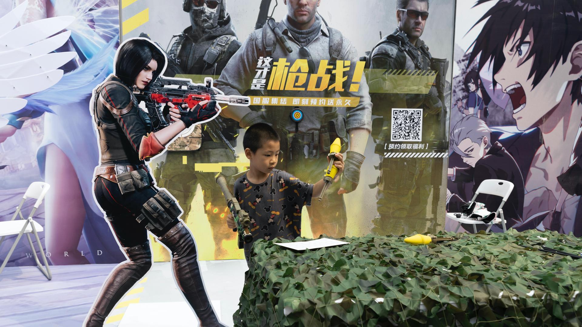 A child plays with a toy gun during a promotion for online games in Beijing on Aug. 29, 2020. China is banning children from playing online games for more than three hours a week, the harshest restriction so far on the game industry as Chinese regulators 