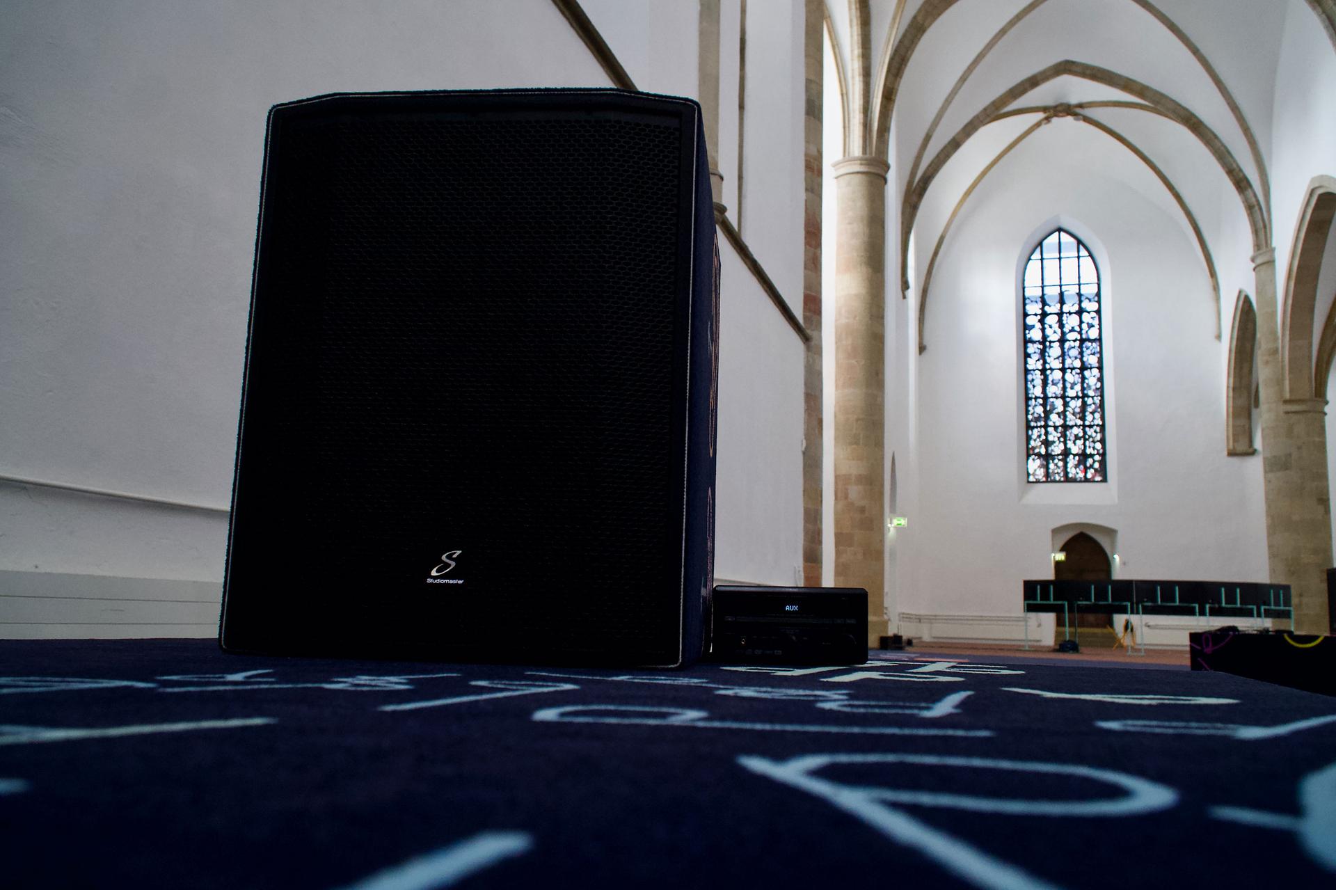 An up-close image of a speaker within a church with high ceilings.