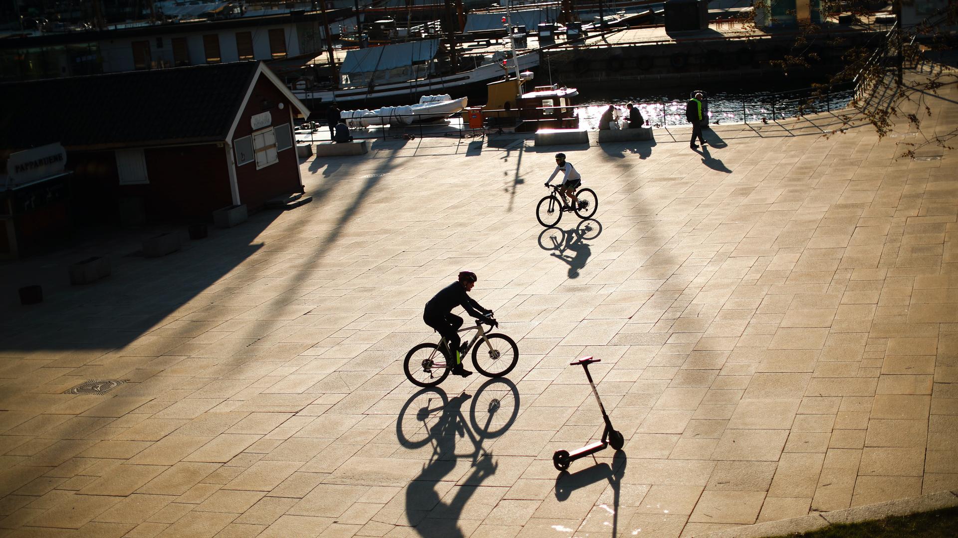 People ride their bicycles at the marina port in Oslo, Norway