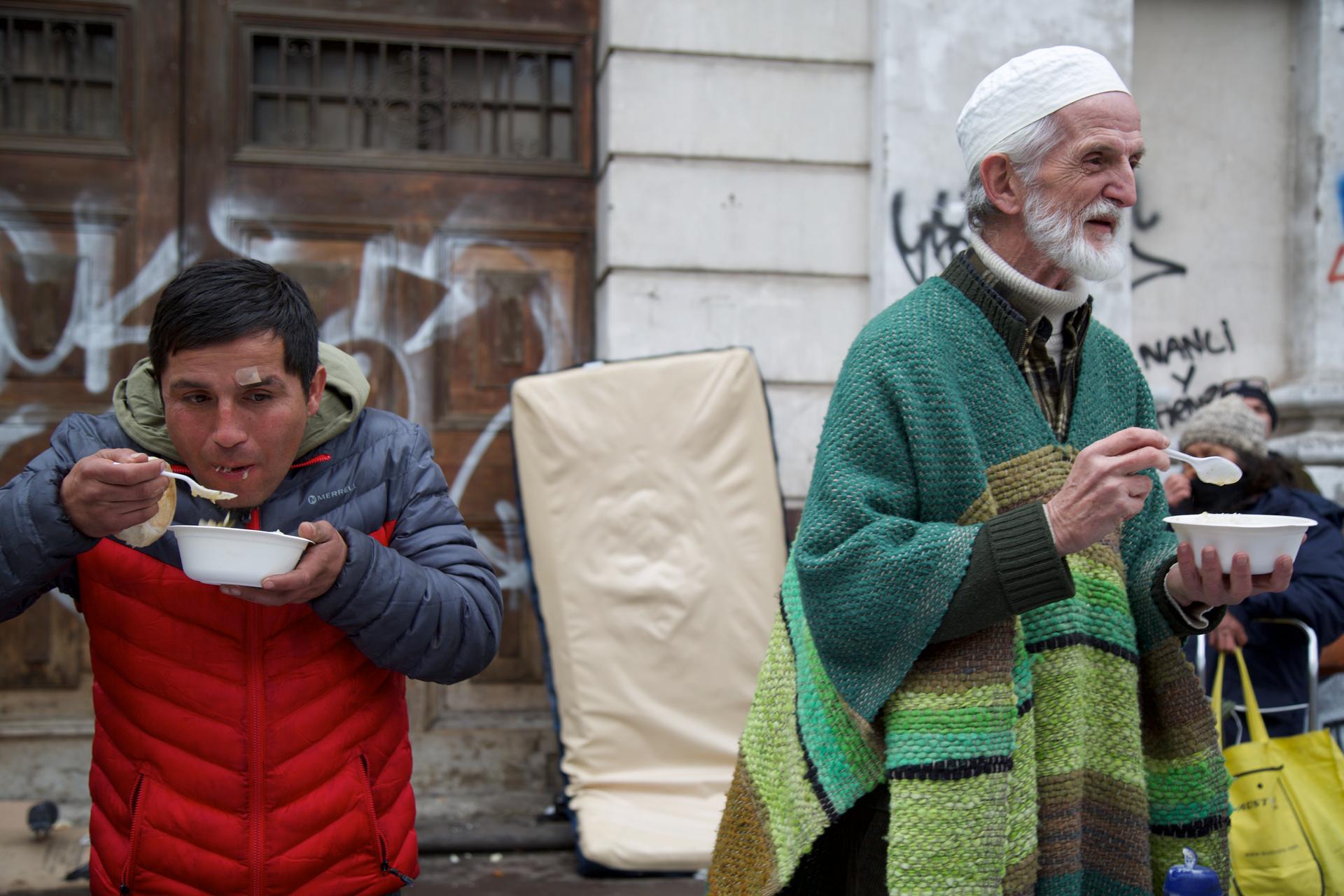 Chilean Muslims and people from other religious communities eating a meal from bowls, outside at the weekly soup kitchen in Santiago, Chile.