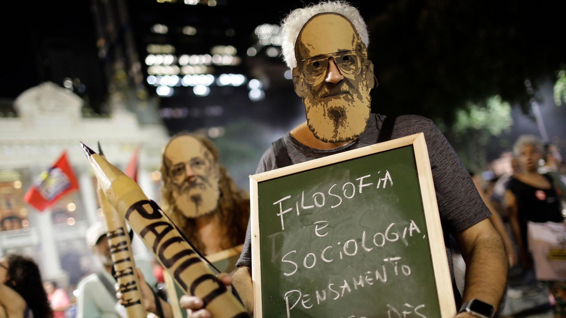 People wear masks of Paulo Freire during a protest against a massive cut in the education budget imposed by the administration of Brazilian President Jair Bolsonaro at Cinelandia square, in Rio de Janeiro, Brazil, Thursday, May 30, 2019.