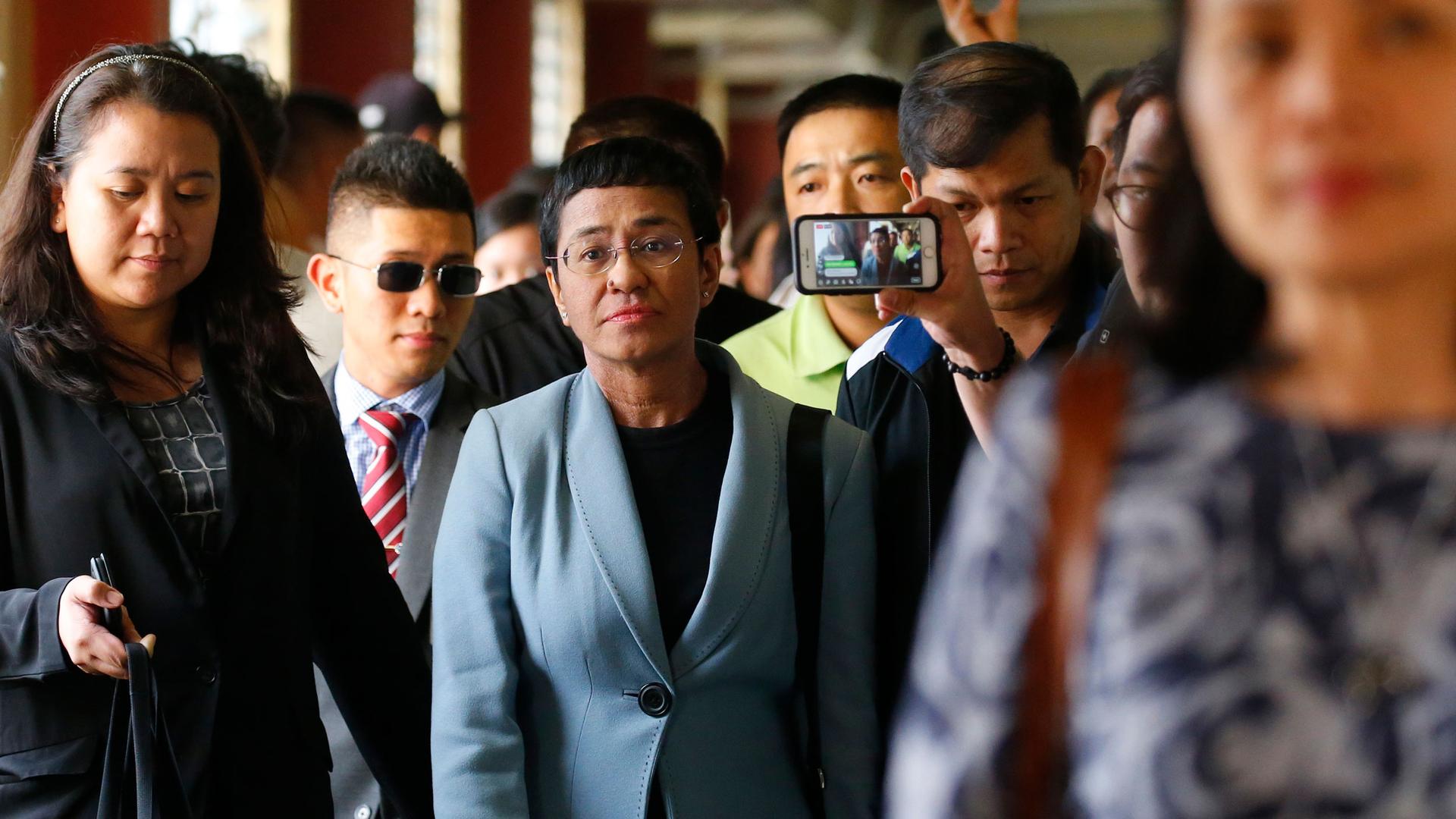 Maria Ressa, center, the award-winning head of a Philippine online news site Rappler, is escorted into the court room to post bail at a Regional Trial Court following an overnight arrest by National Bureau of Investigation agents on a libel case Thursday,