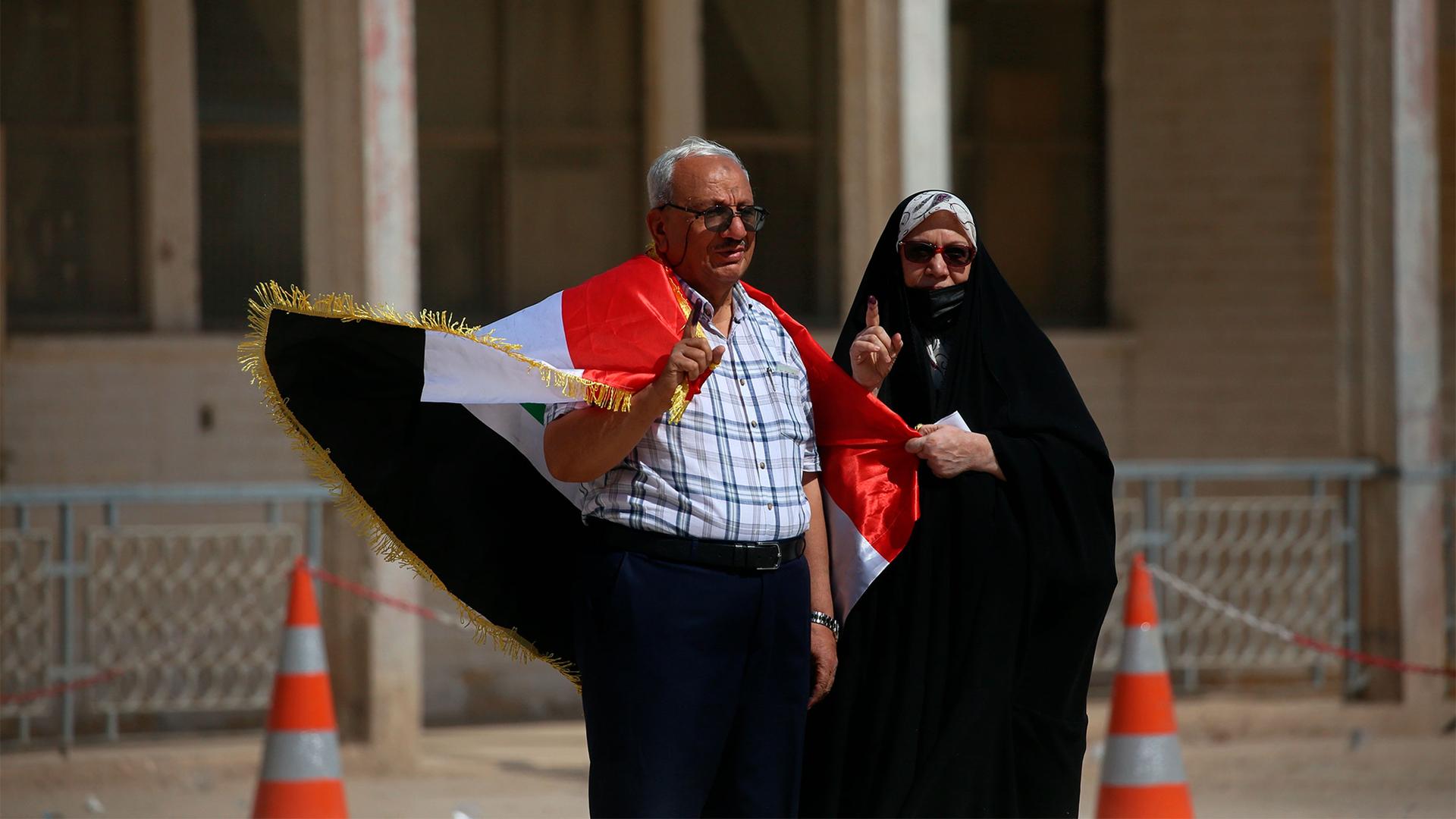 A man and his wife show their ink-marked fingers after casting their votes inside a polling station in the country's parliamentary elections in Najaf, Iraq