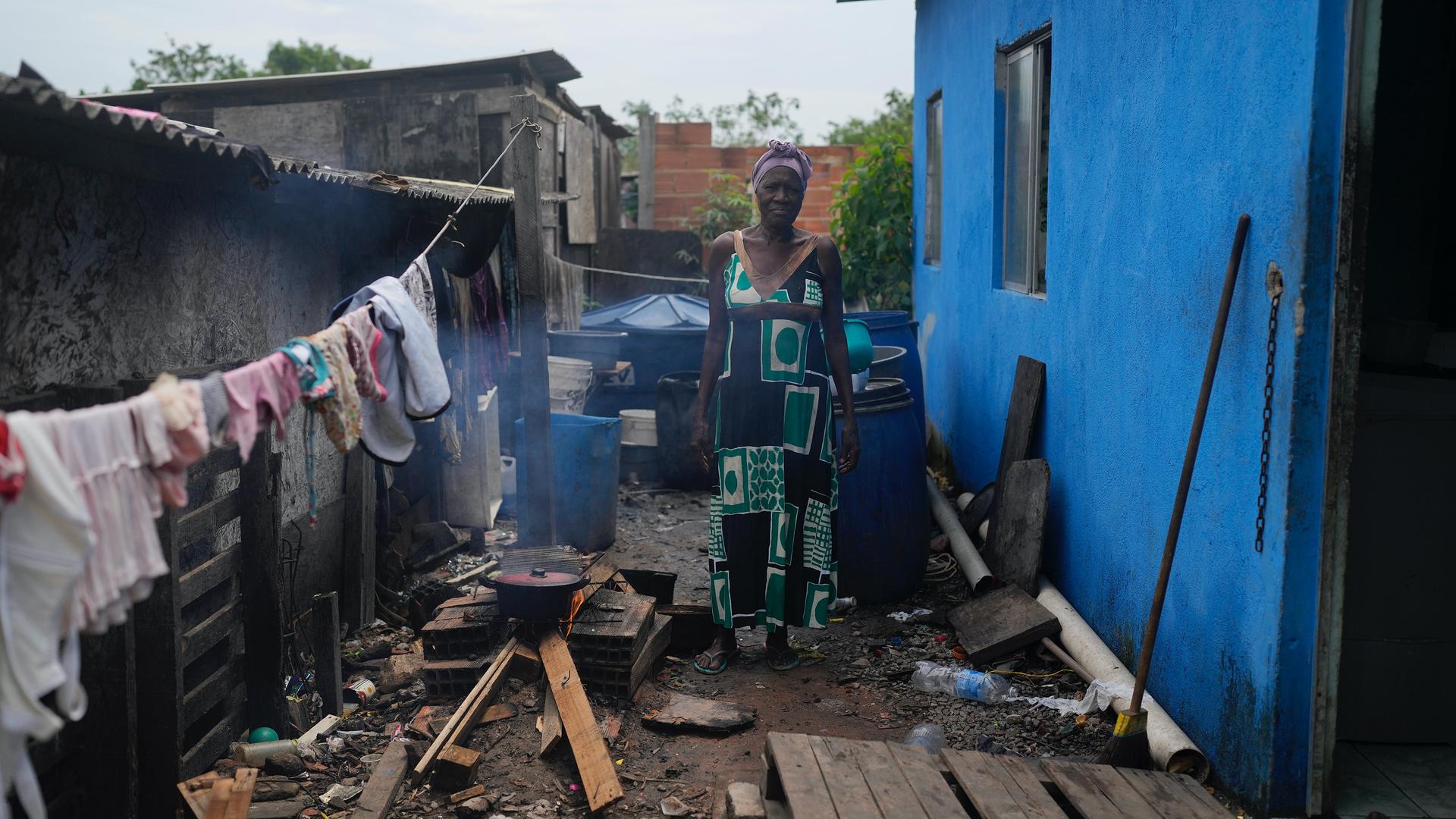 Lady Laurentino, 74, poses for a photo next to a wood fire she uses to cook near the door of her home in the Jardim Gramacho favela of Rio de Janeiro, Brazil, Oct. 4, 2021. With the surge in cooking gas prices, Laurentino says she is cooking with wood bec